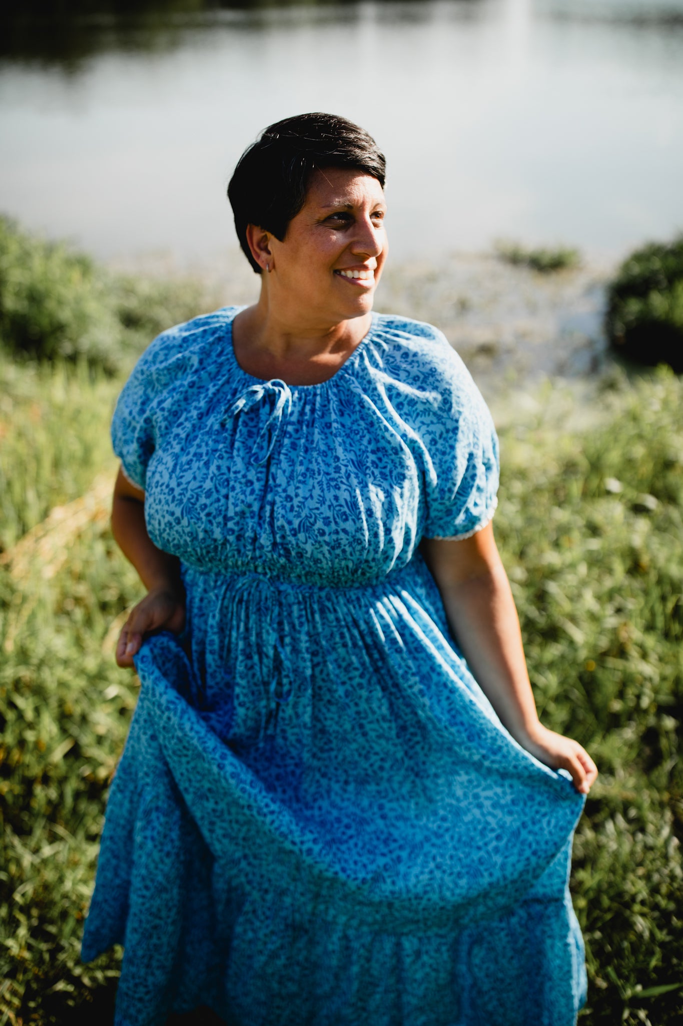Woman wearing a blue modest nursing dress standing by a body of water.