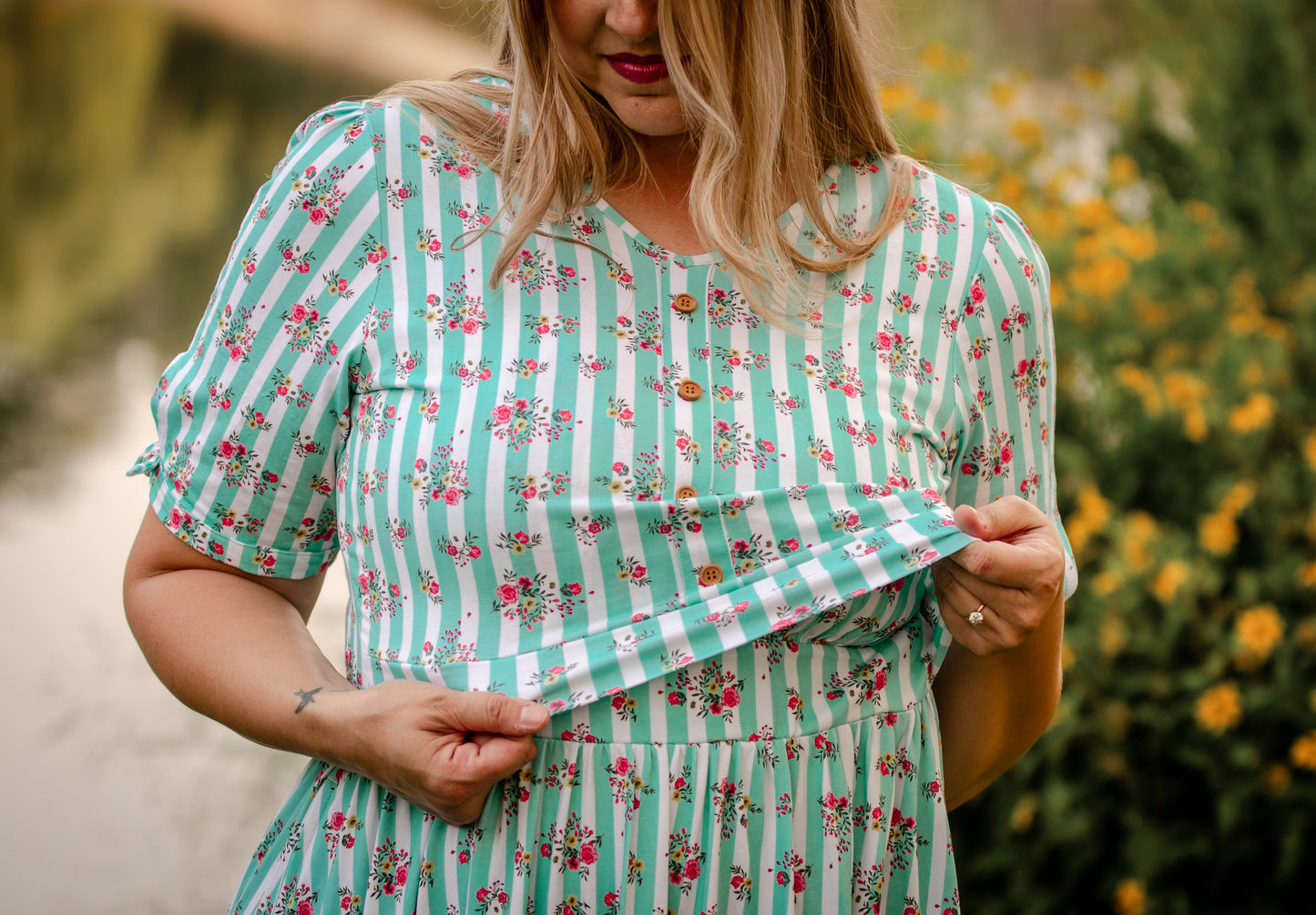 Woman wearing a green and white striped modest nursing dress with floral patterns outdoors.