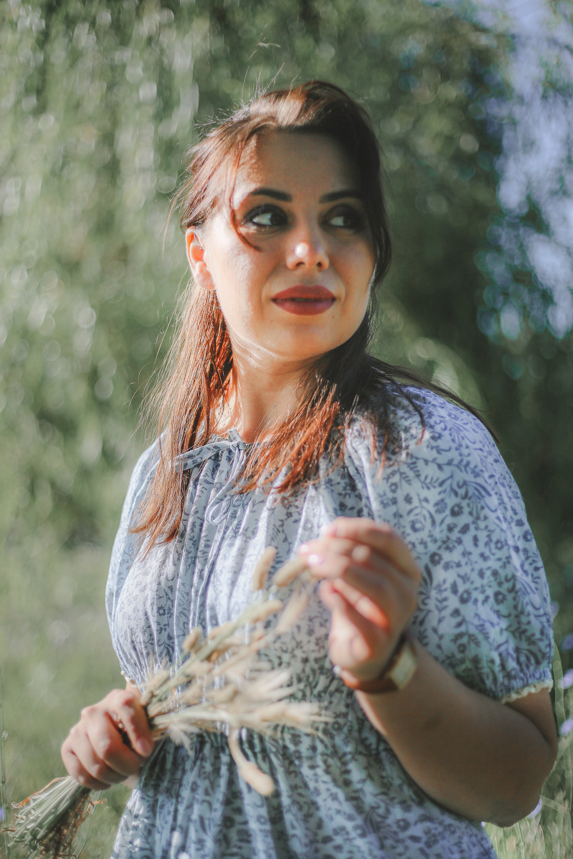 Woman holding dried flowers in a modest blue nursing dress