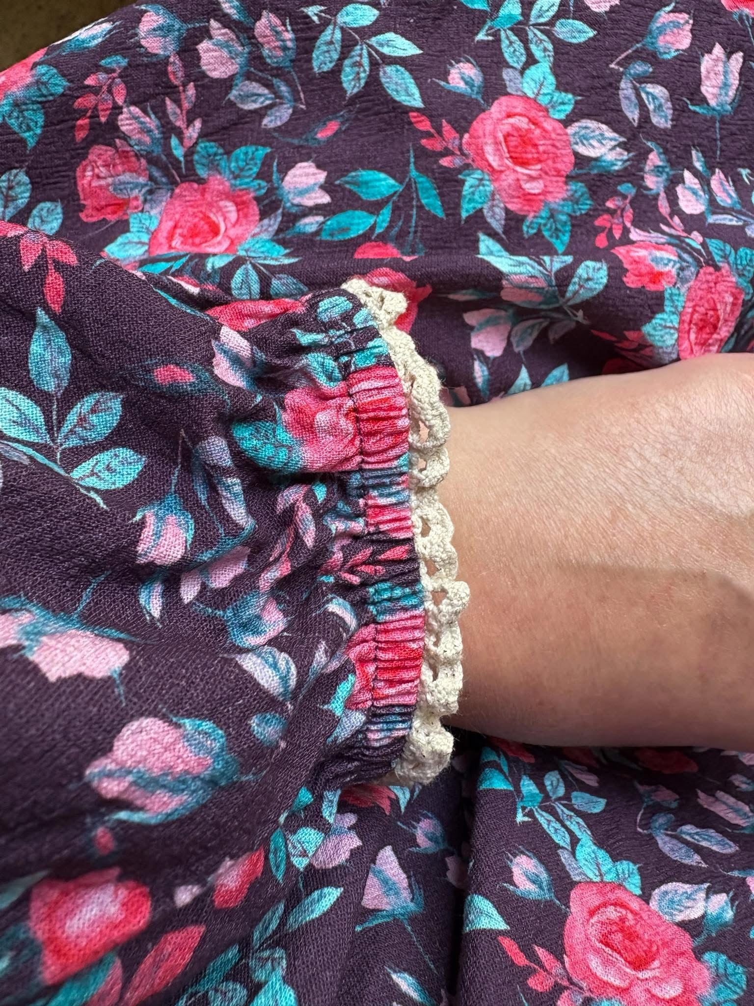 Close-up of floral-patterned fabric with a bracelet on a wrist.