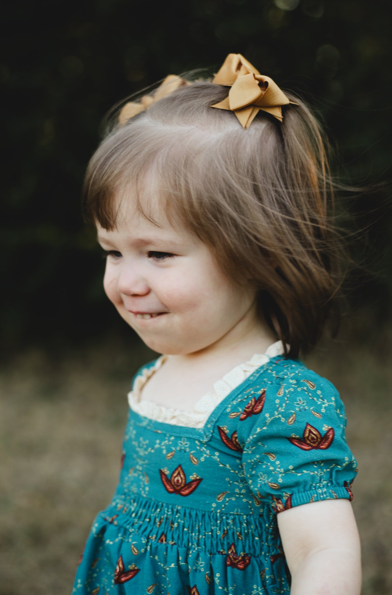 Young girl wearing modest dress with bow outdoors