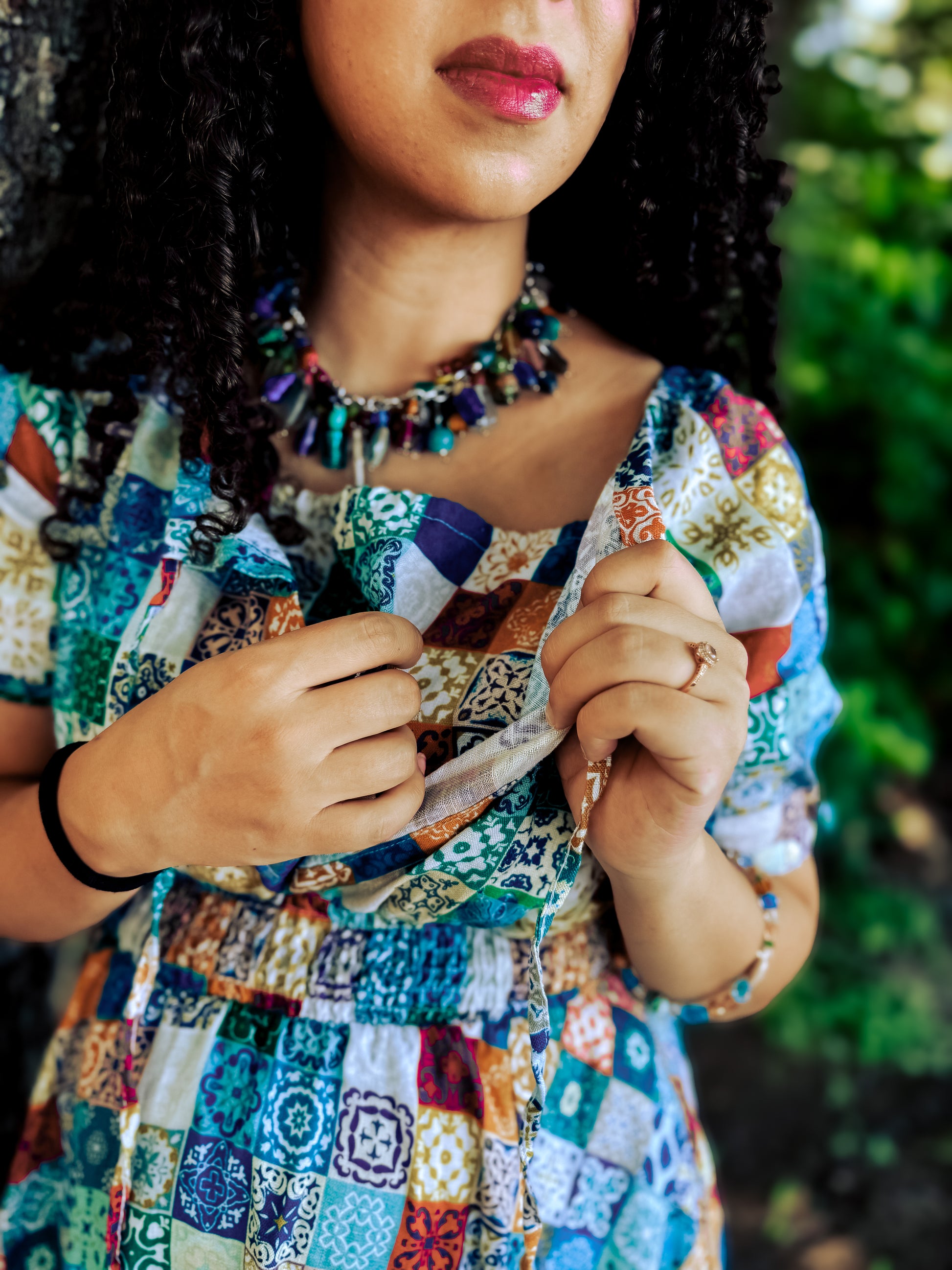 Person wearing a colorful patterned modest nursing dress with a blurred green background