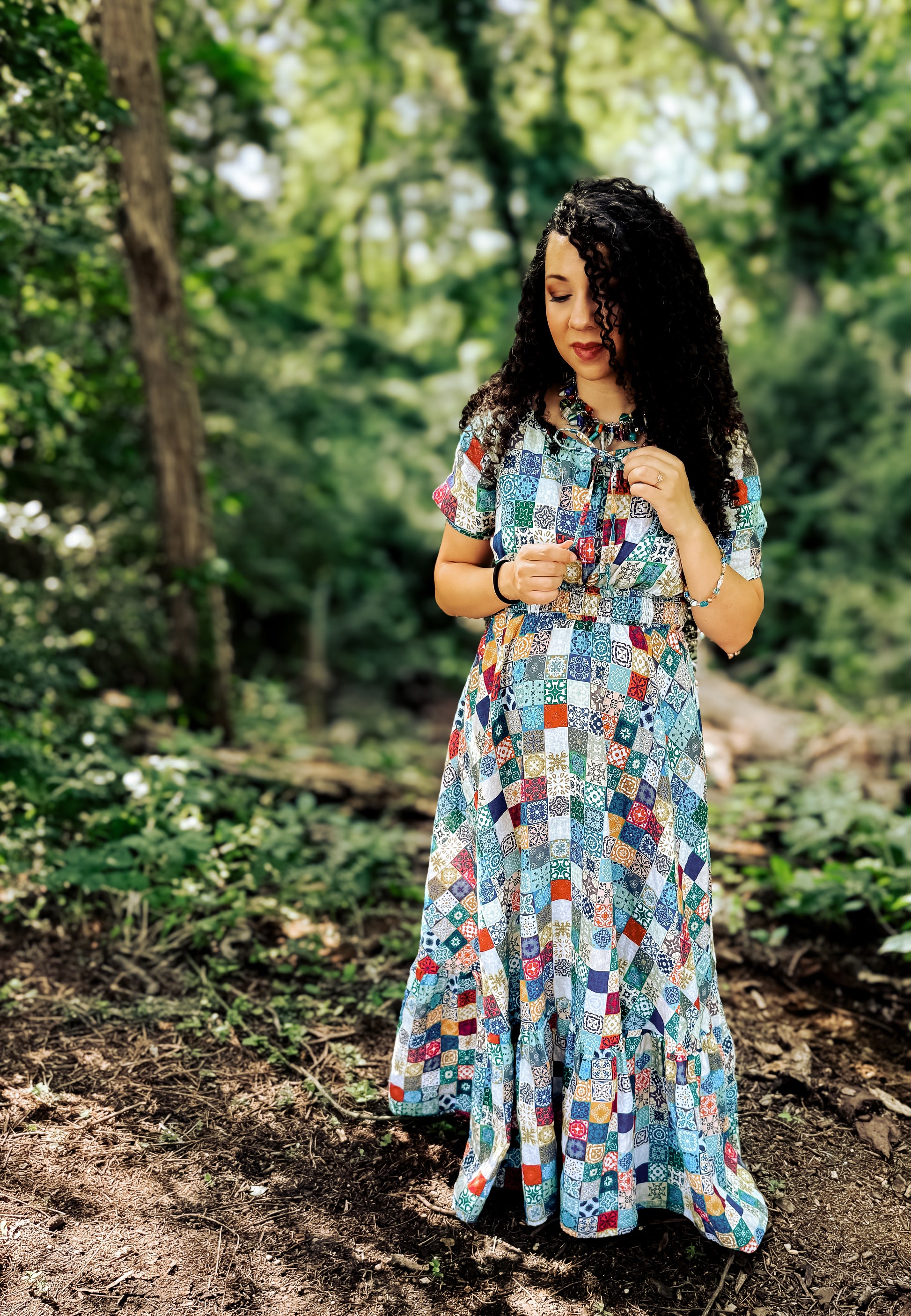 Woman in a colorful patchwork modest nursing dress standing in a forest