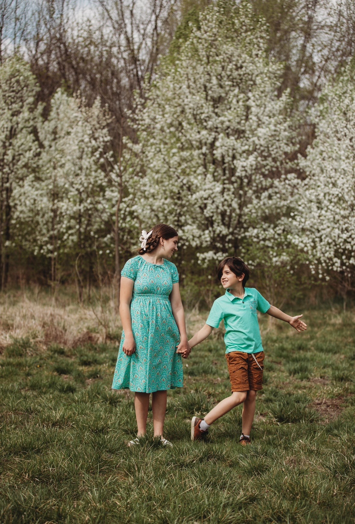 Young girl wearing a modest green dress with her brother wearing a green shirt