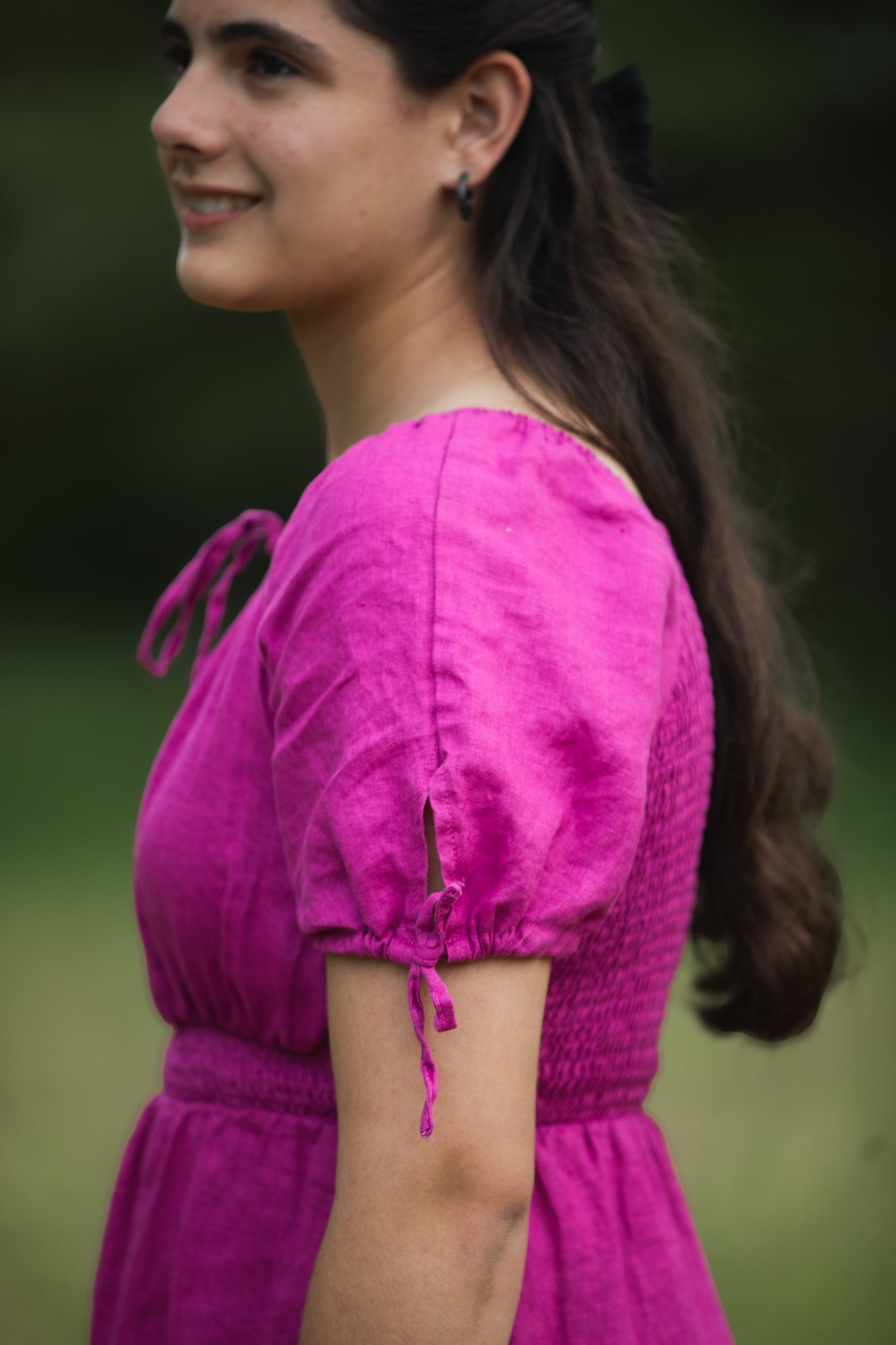 Woman wearing a pink modest nursing dress with a blurred green background