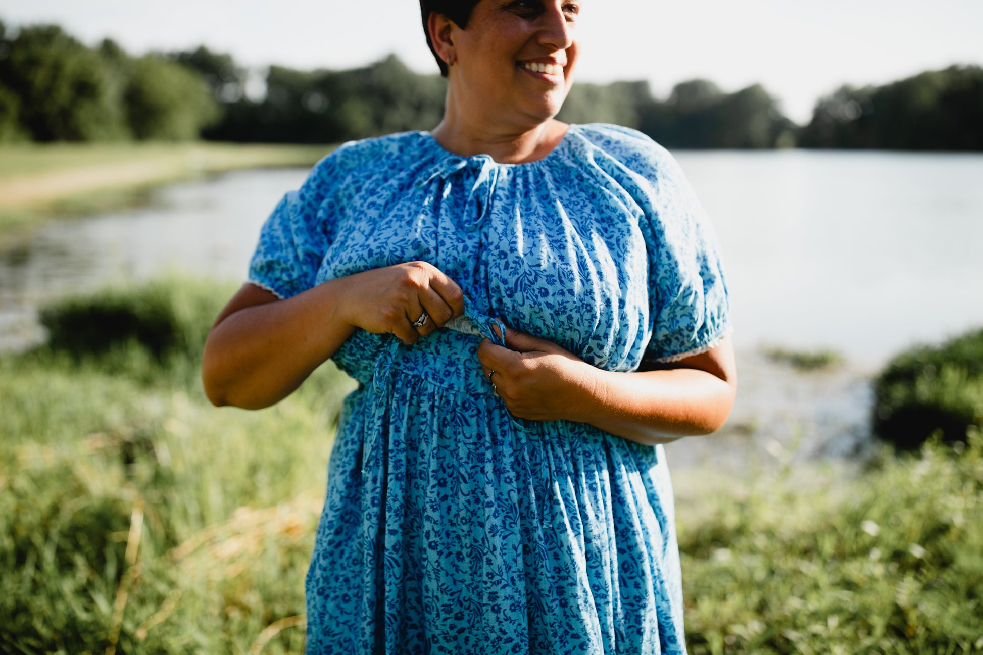 Woman in a blue modest nursing dress standing outdoors by a body of water