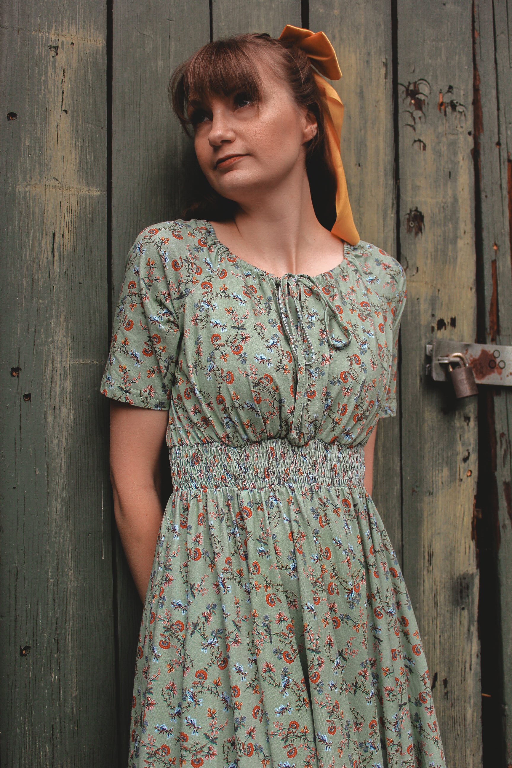 Woman in modest nursing floral dress by wall