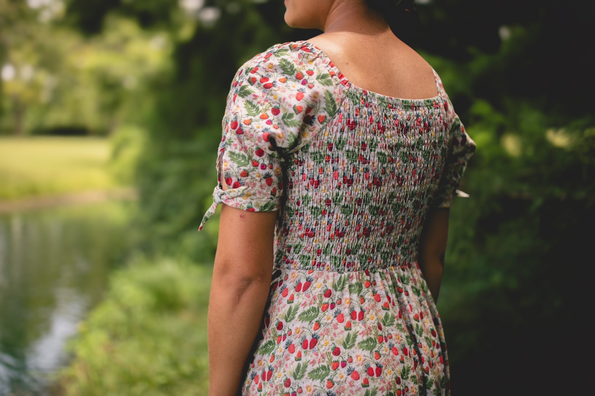 Woman wearing a floral modest nursing dress standing outdoors with greenery in the background