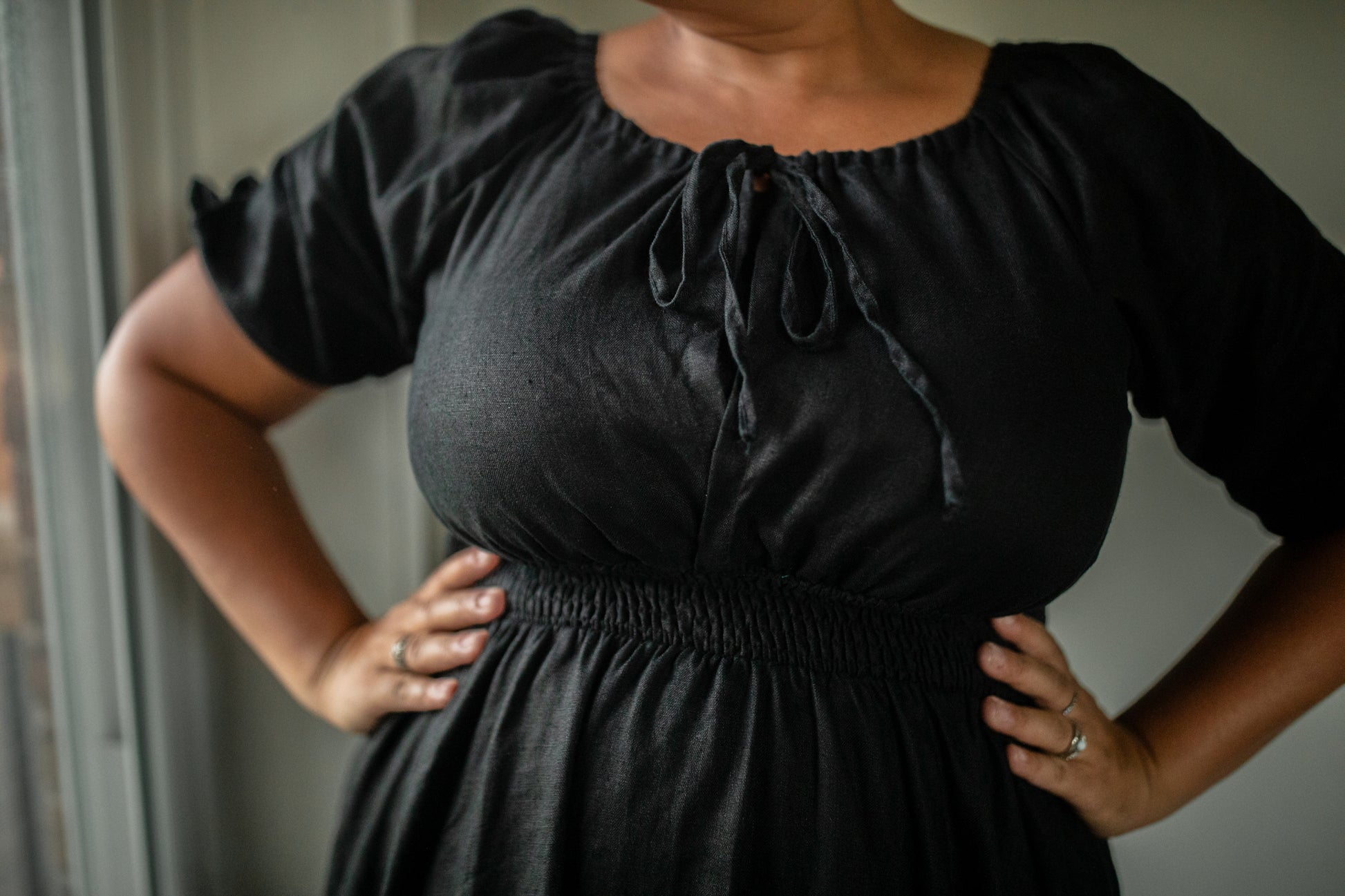 Person wearing a black modest nursing dress with puff sleeves against a neutral background