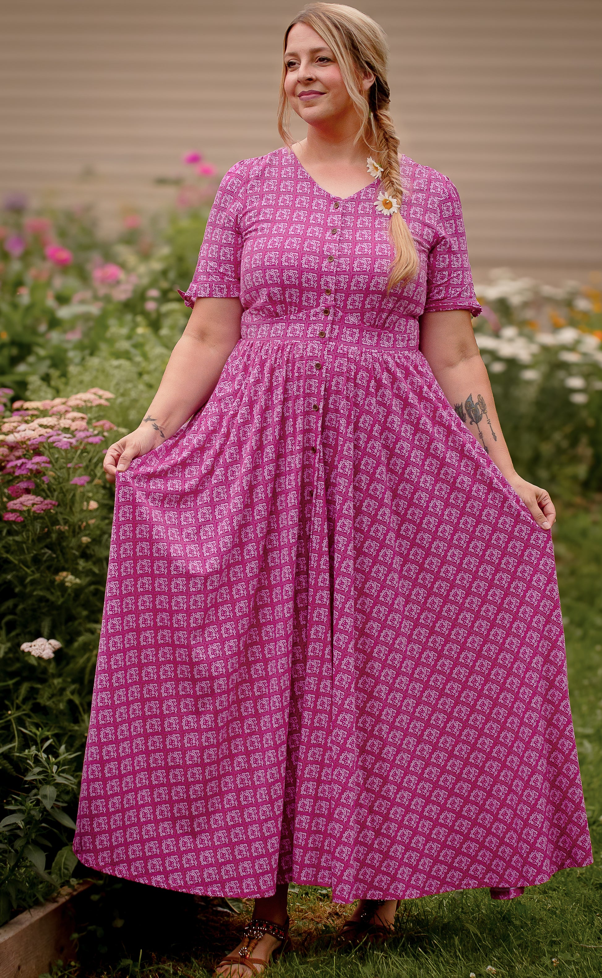 Woman wearing a pink modest nursing dress with a pattern standing in a garden.