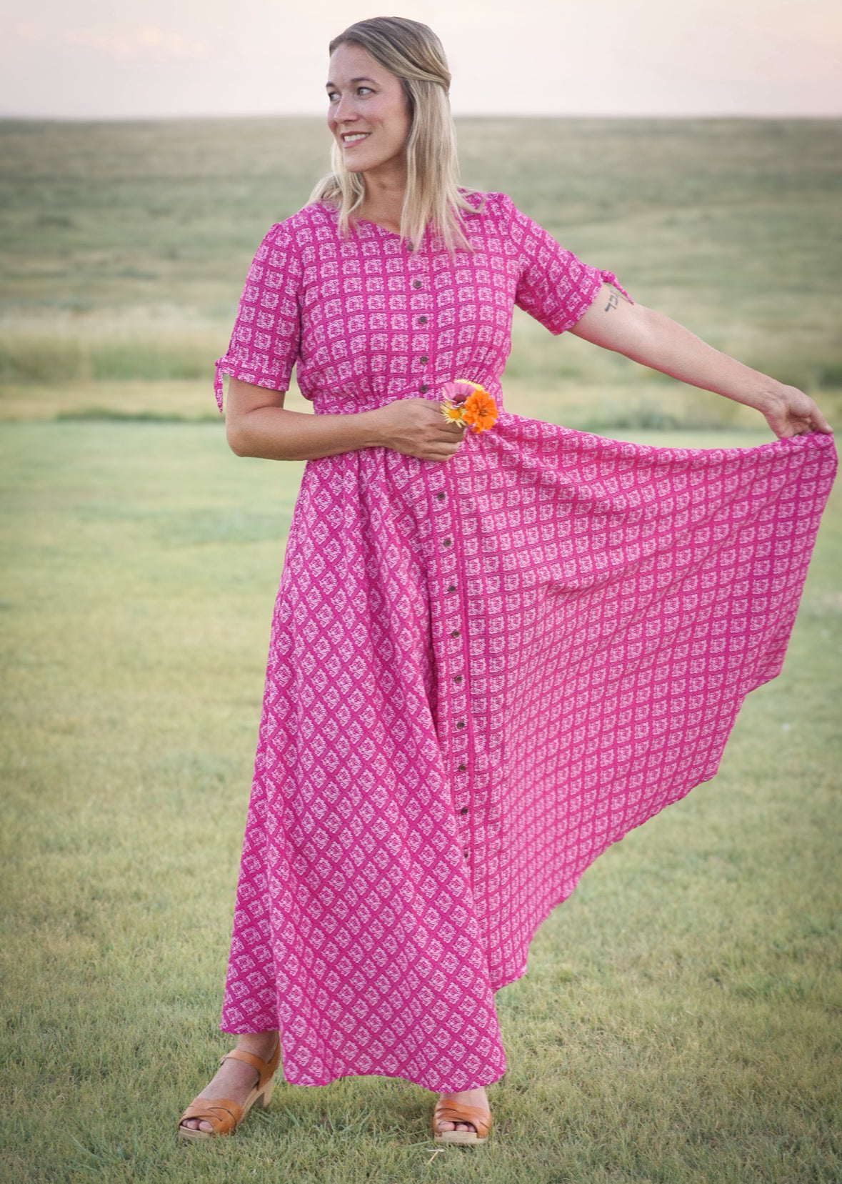 Woman in a pink modest nursing dress standing in a grassy field