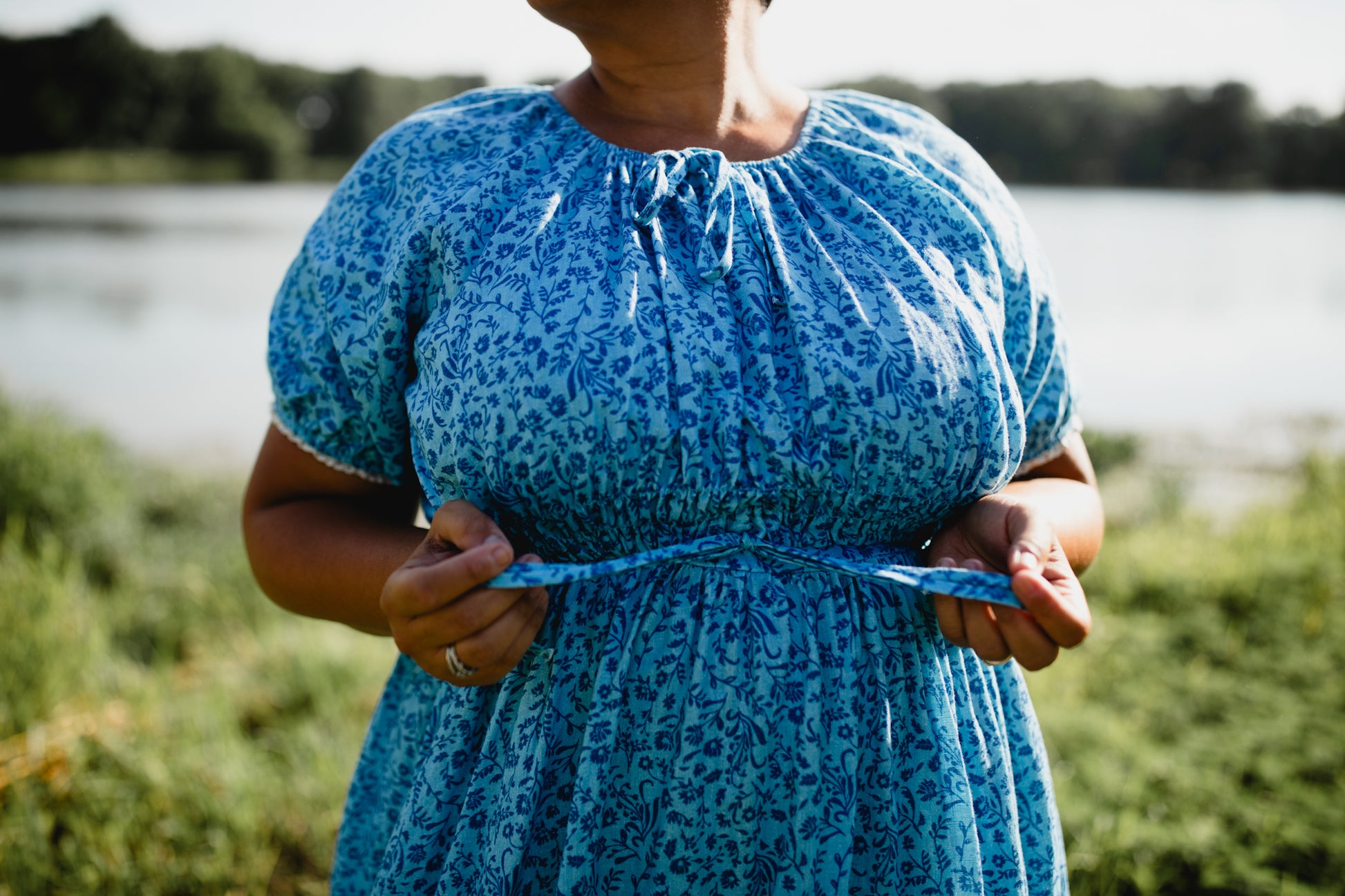 Person wearing a blue floral modest nursing dress standing outdoors with a natural background