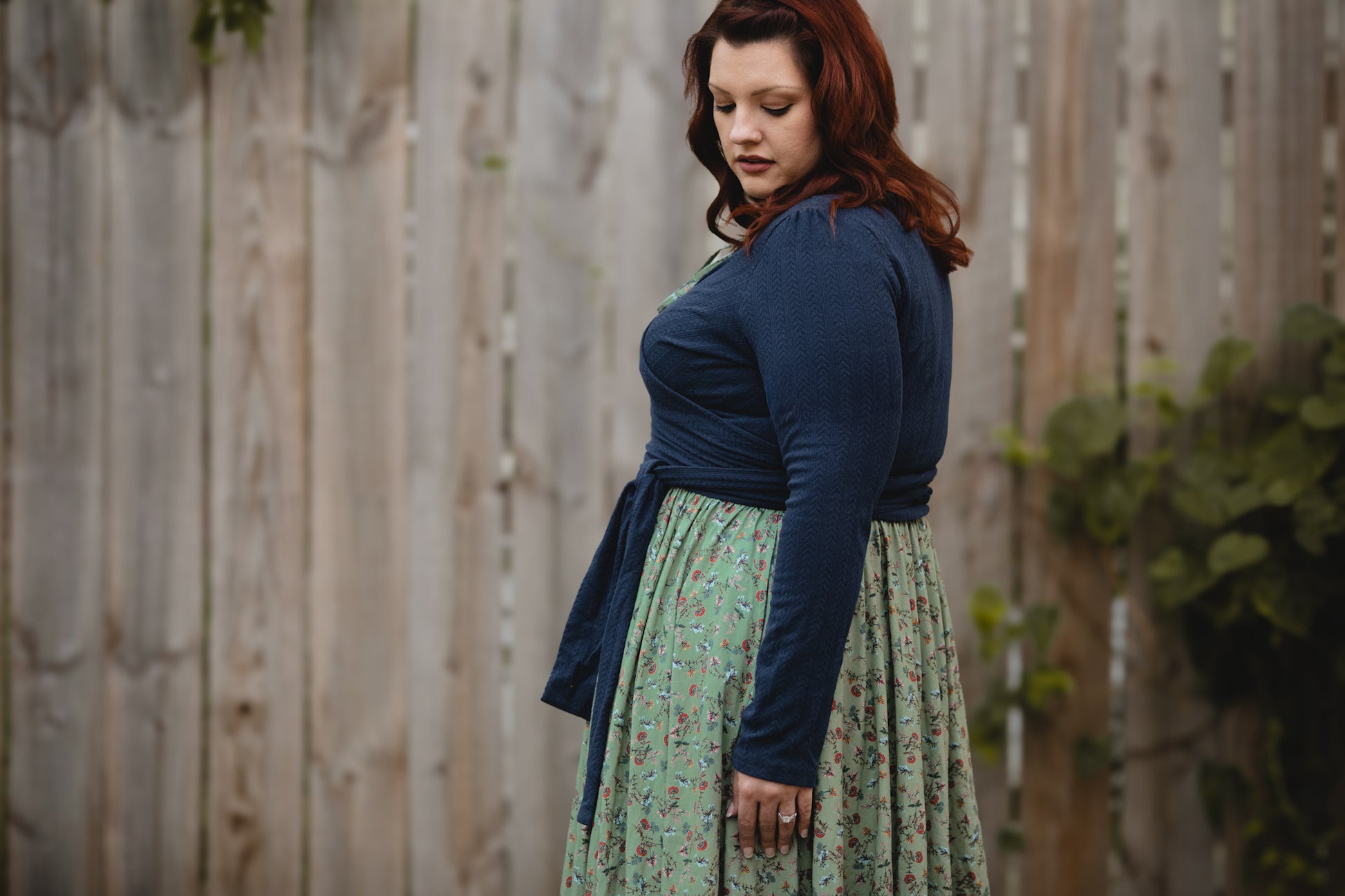 Woman in modest nursing floral dress by fence