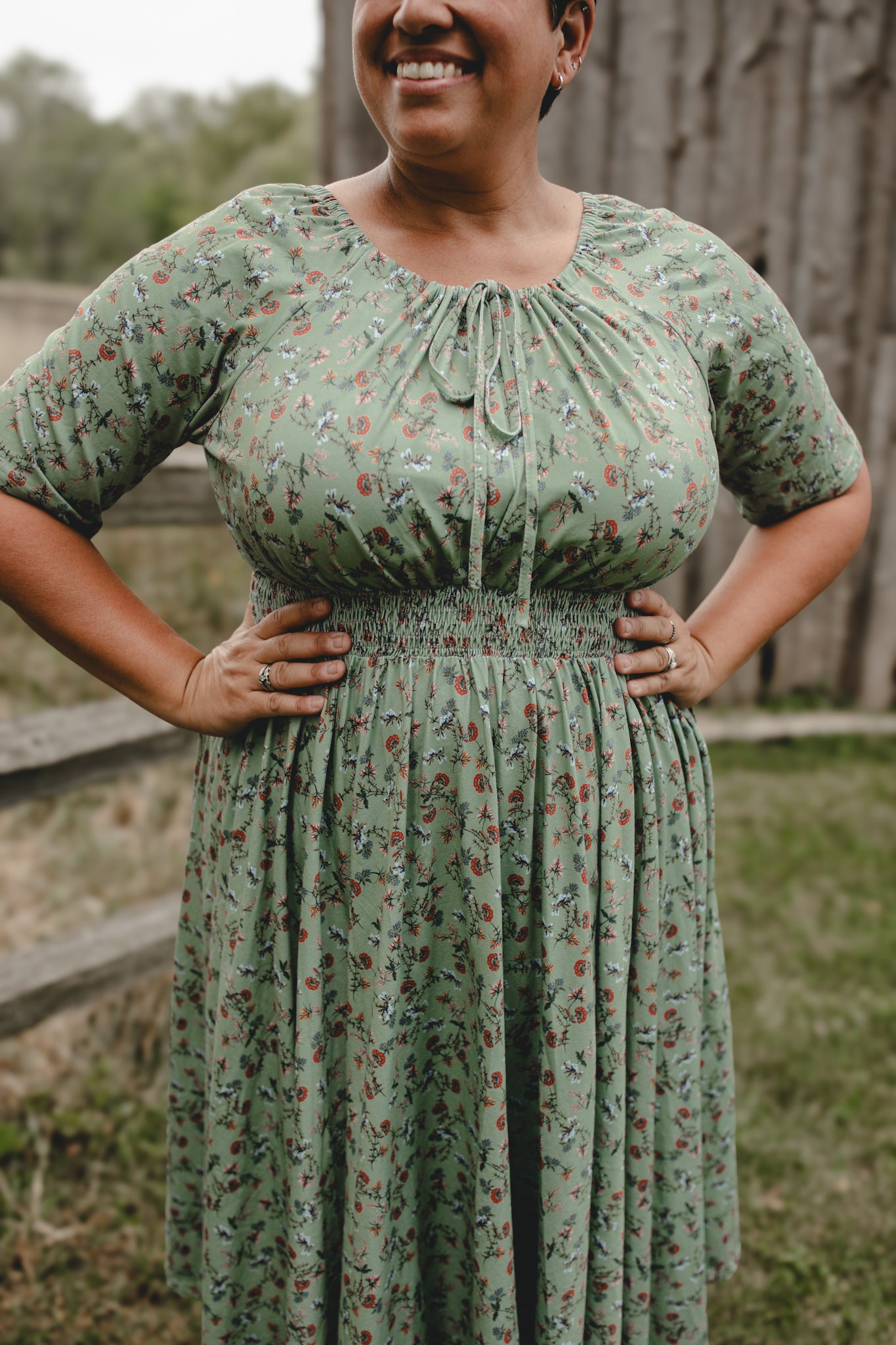 Woman in modest nursing floral dress by fence