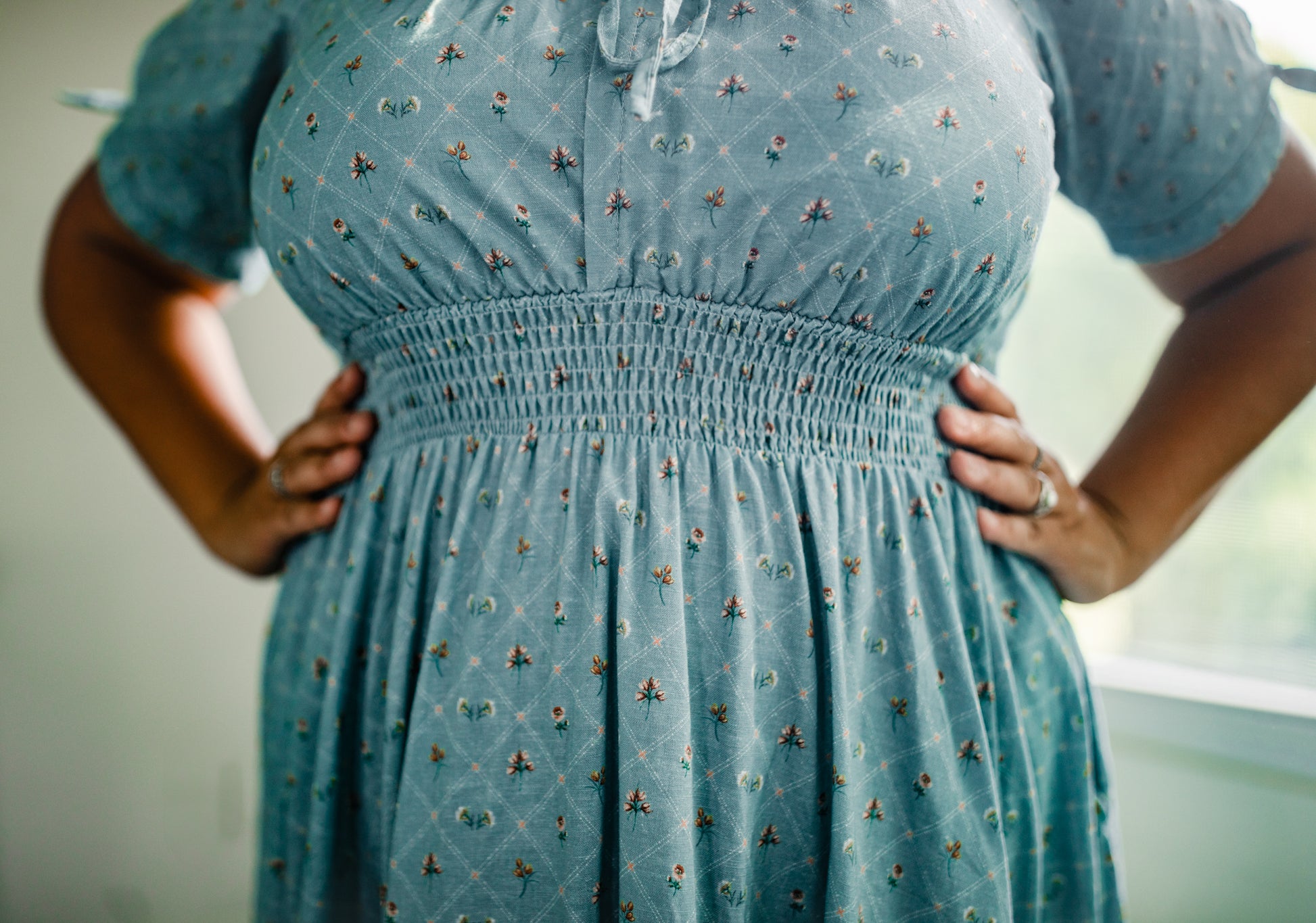 Blue modest nursing dress with floral pattern worn by a person, blurred background