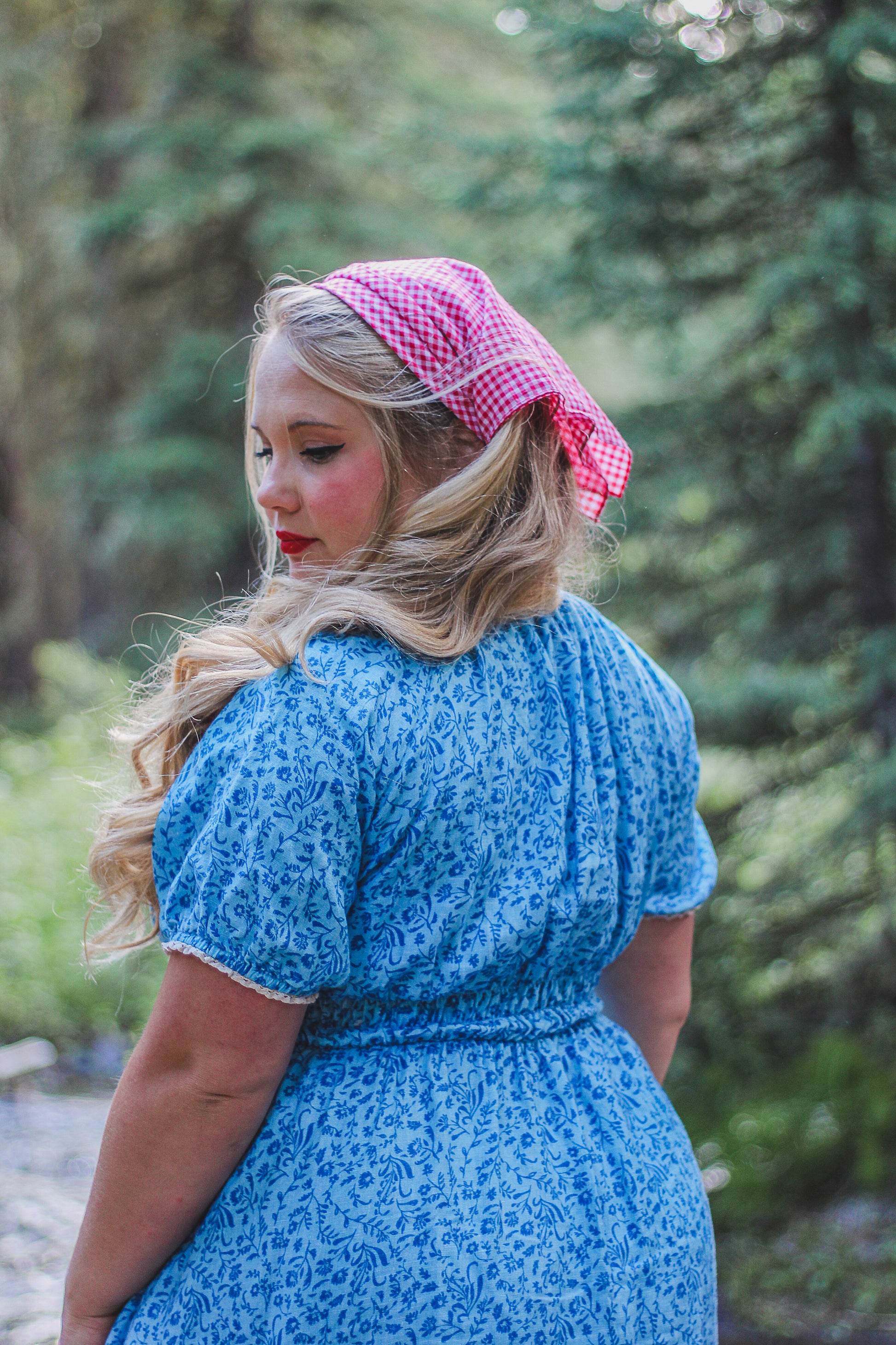 Woman wearing a blue modest nursing dress and pink headscarf in a forest setting