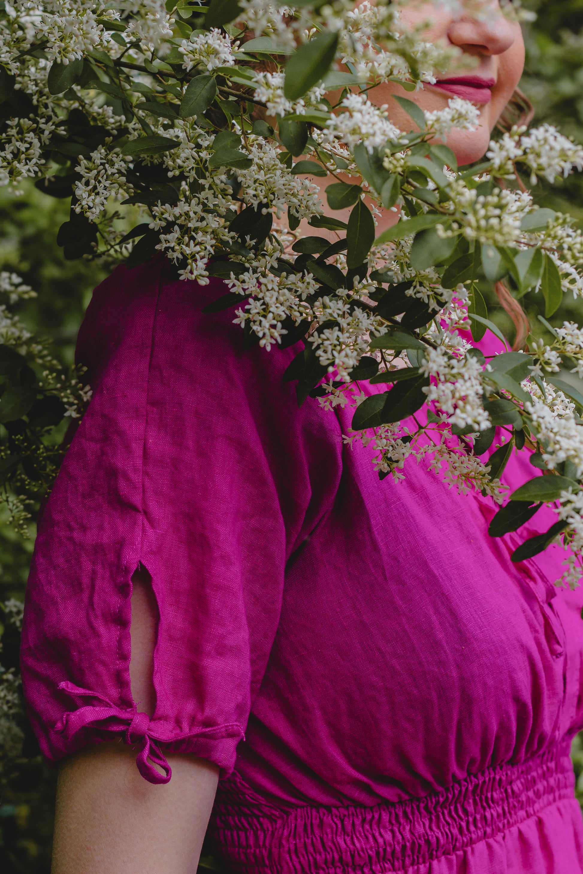 Person wearing a bright pink modest nursing dress with floral and greenery in the background