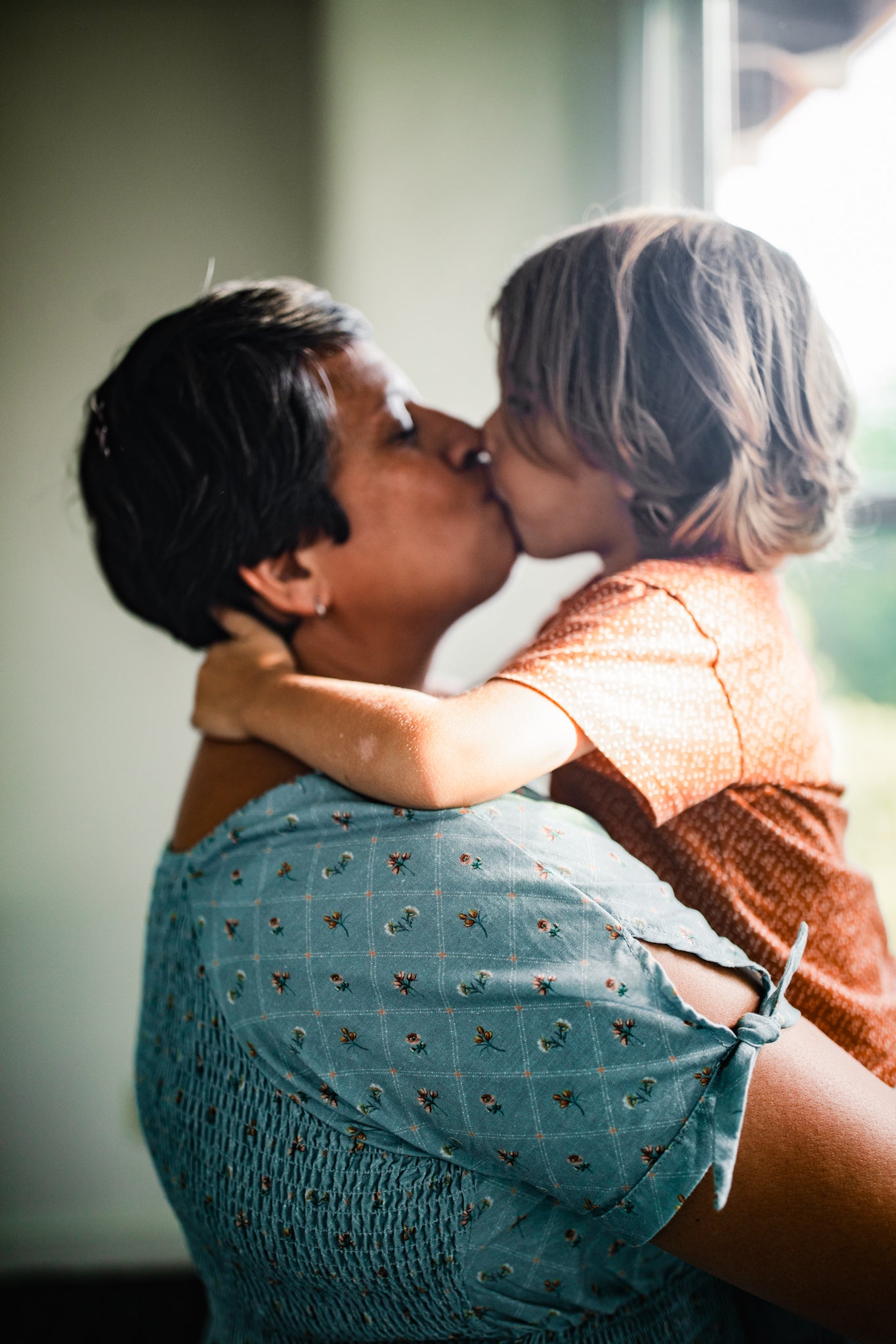 woman in modest nursing dress kissing her child