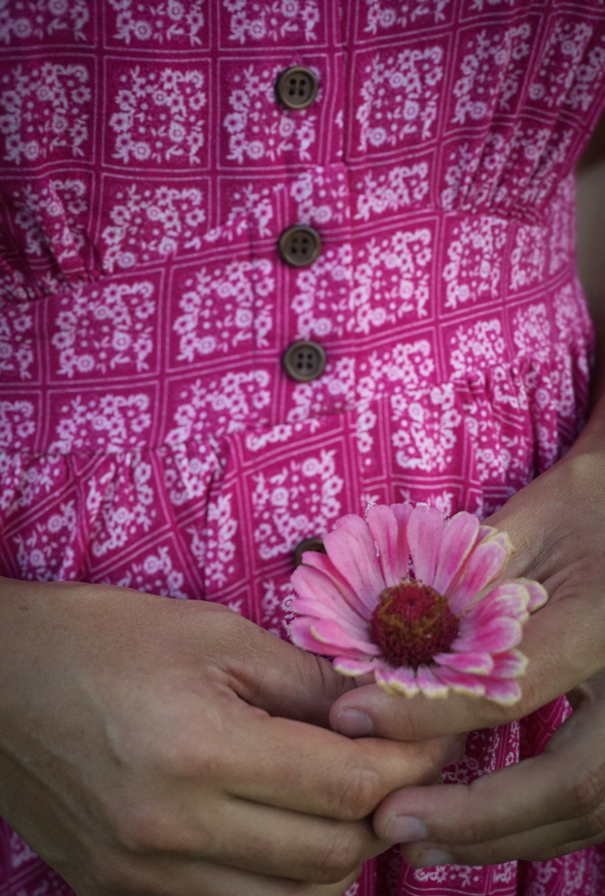 Person wearing a pink floral modest nursing dress holding a pink flower
