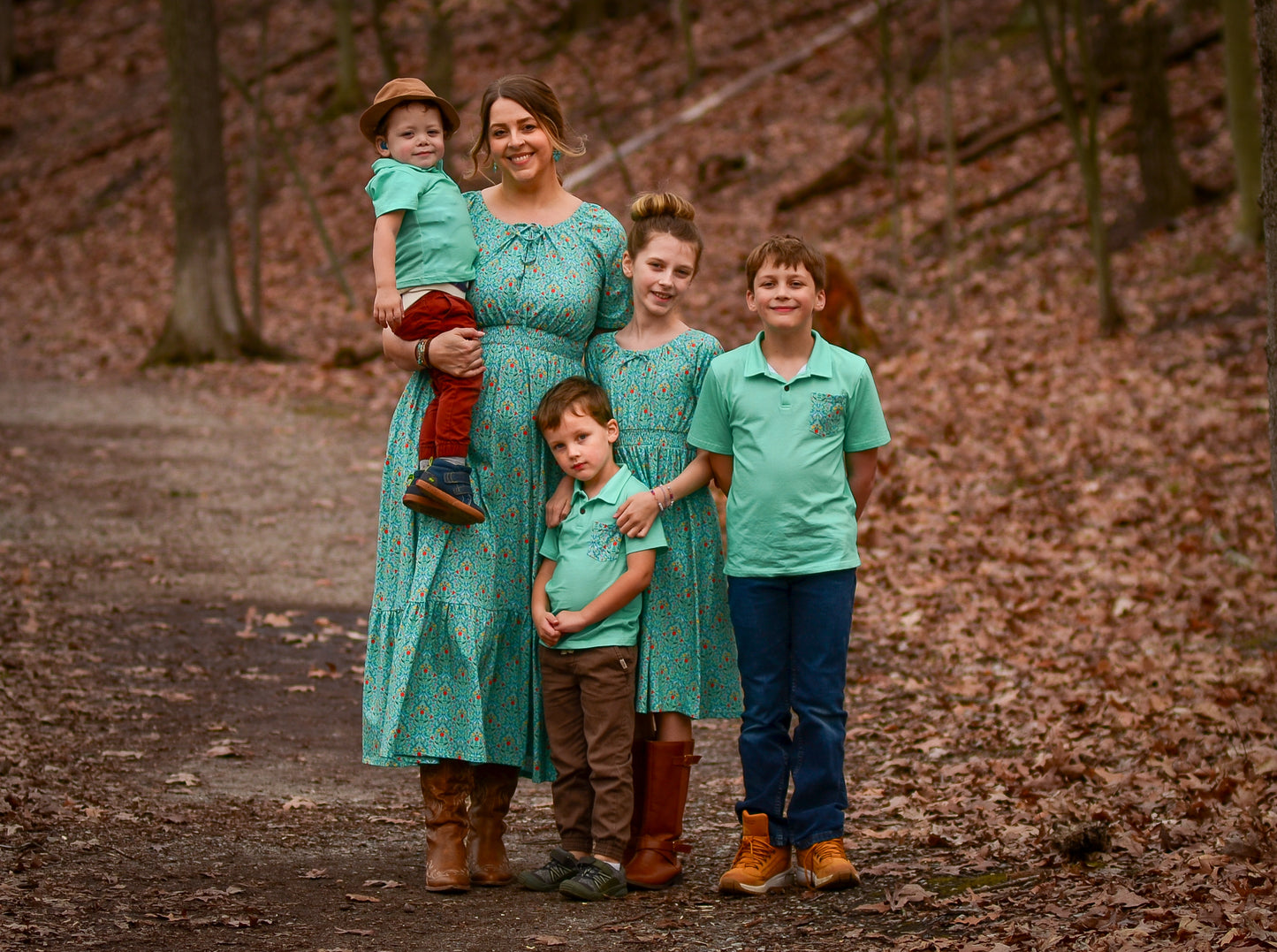 Young girls wearing modest green dresses with their mother in a modest green nursing dress and her brothers