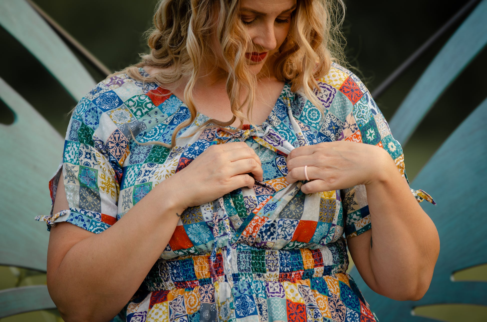 Woman wearing a colorful patchwork modest nursing dress against a blurred background