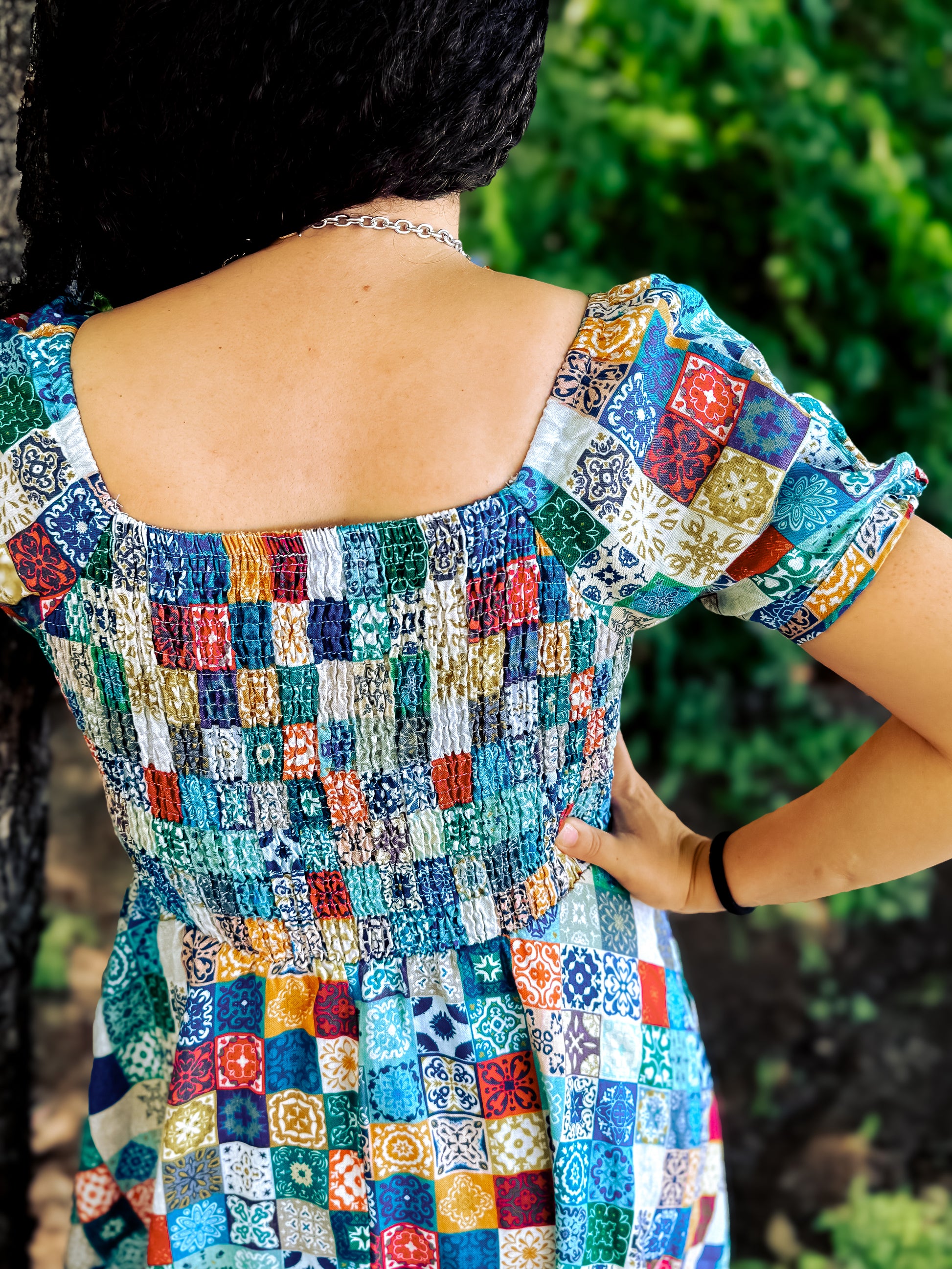 Multicolored patterned modest nursing dress worn by a person with a blurred green background