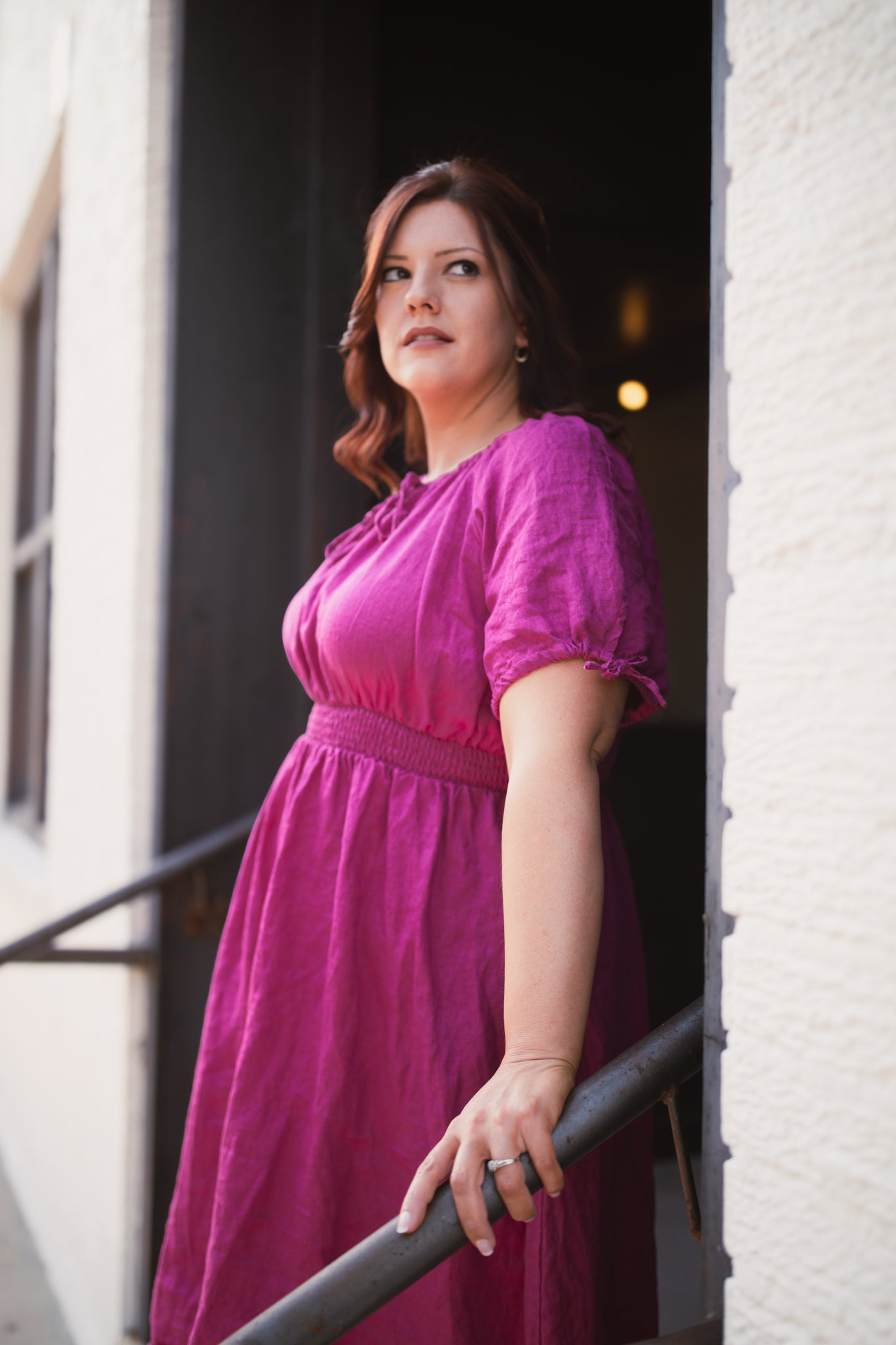 Woman in a pink modest nursing dress standing outside a building
