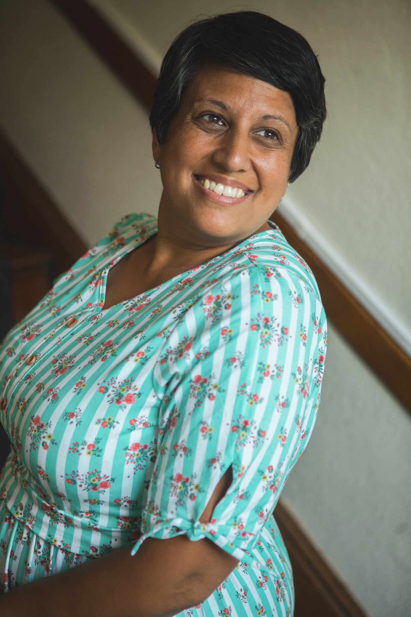Woman wearing a green floral modest nursing dress with a neutral background