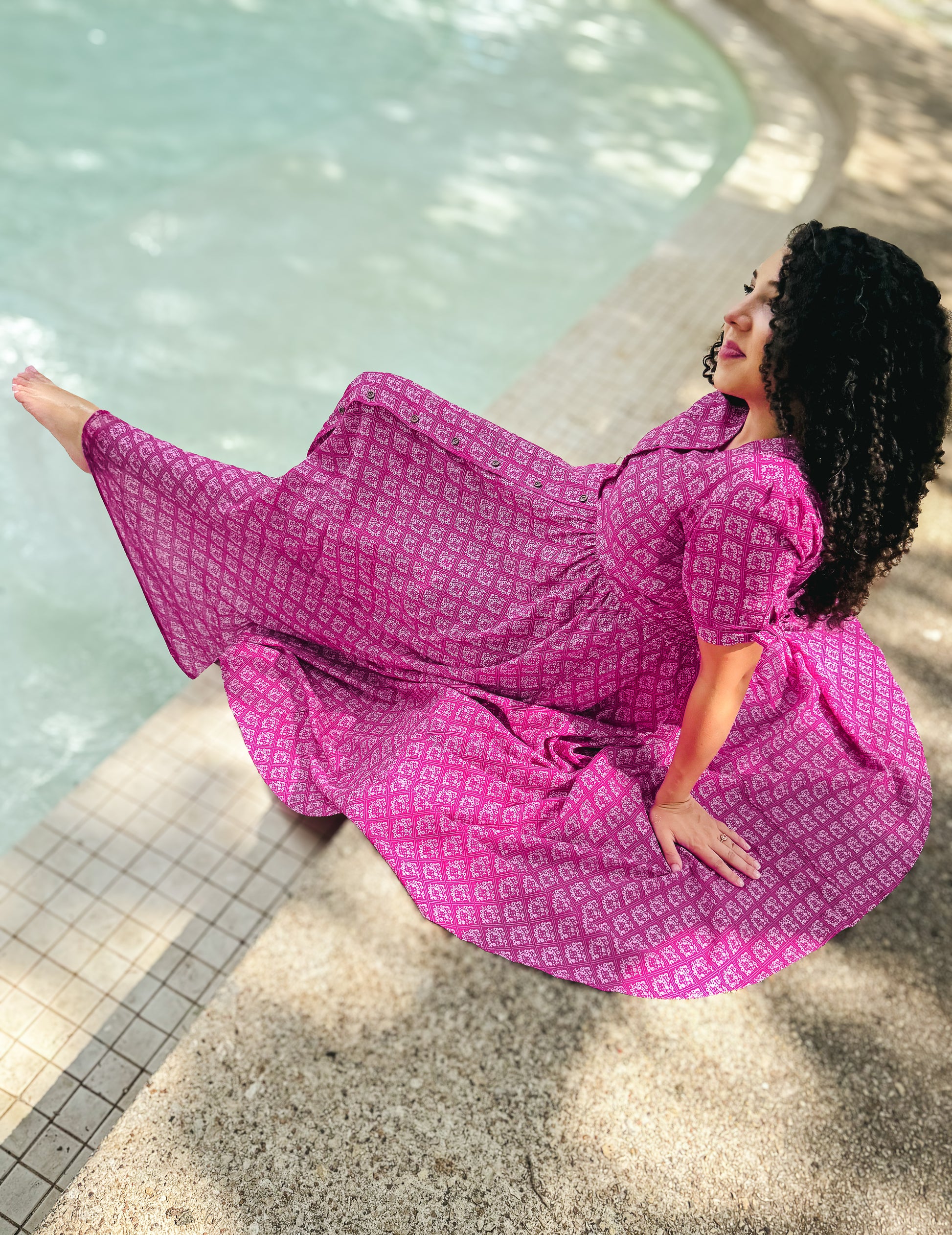 Woman in a pink modest nursing dress sitting by a pool