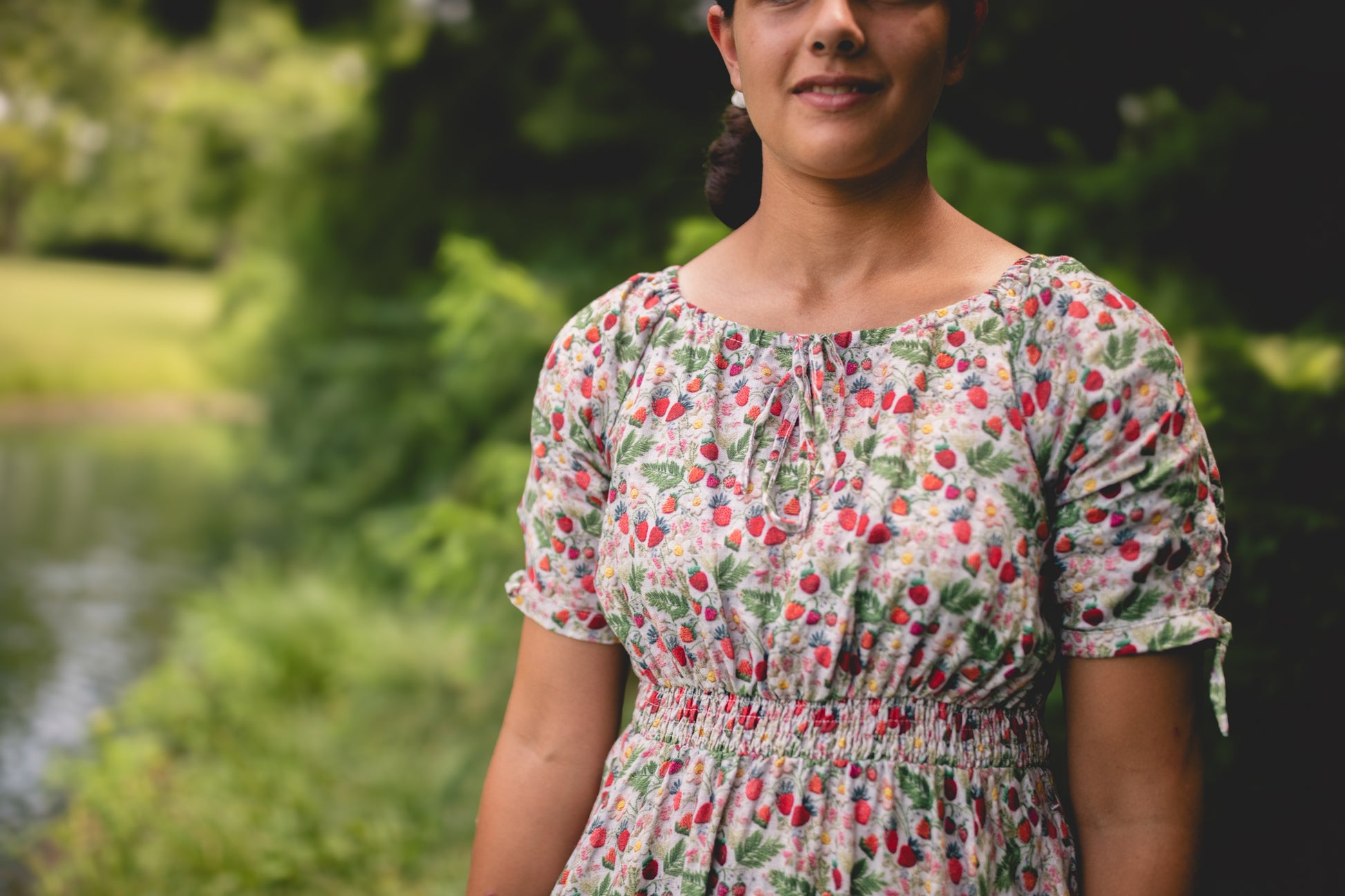 Woman wearing a floral modest nursing dress standing outdoors with greenery in the background