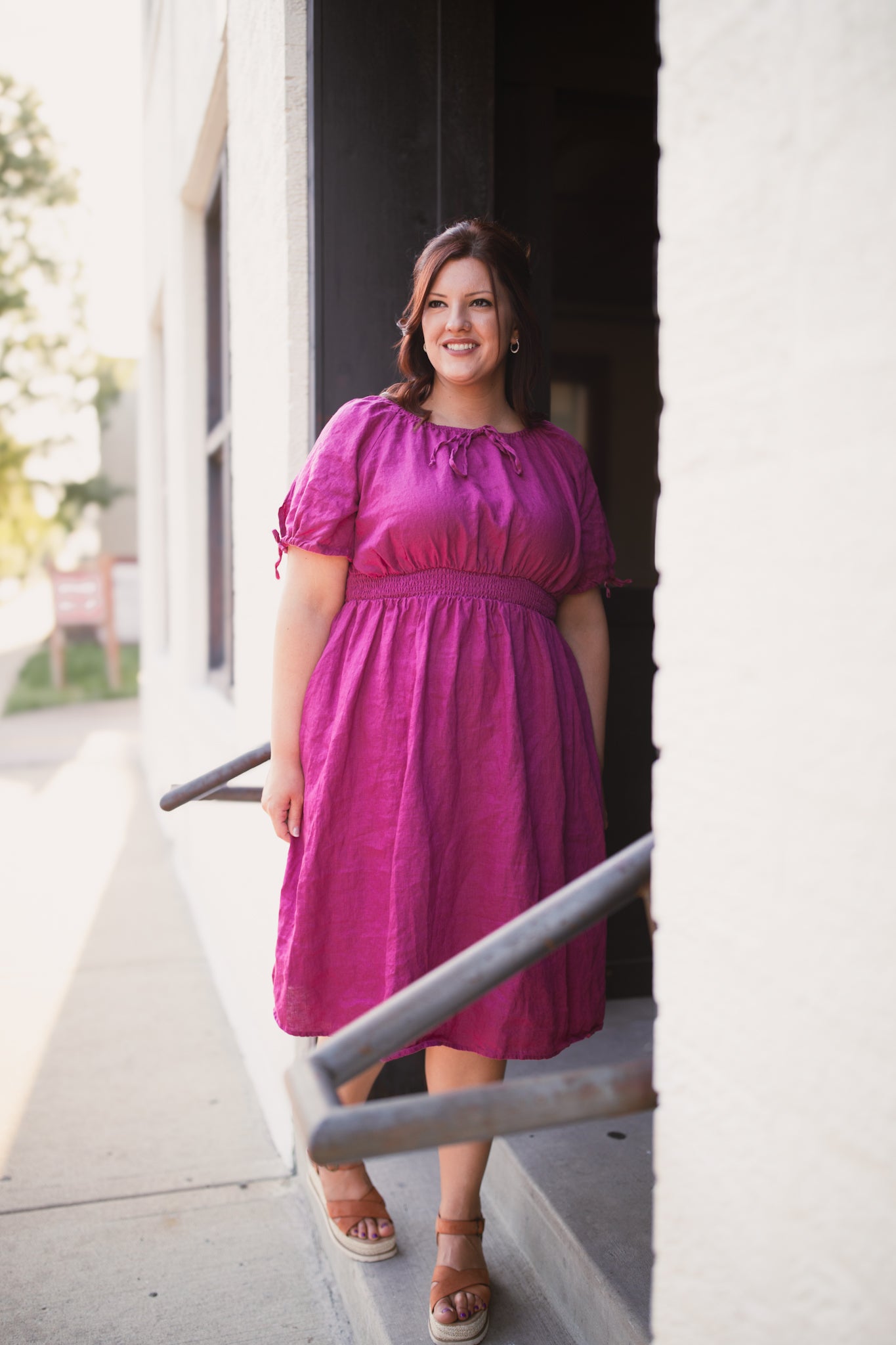 Woman in a pink modest nursing dress standing outside a building