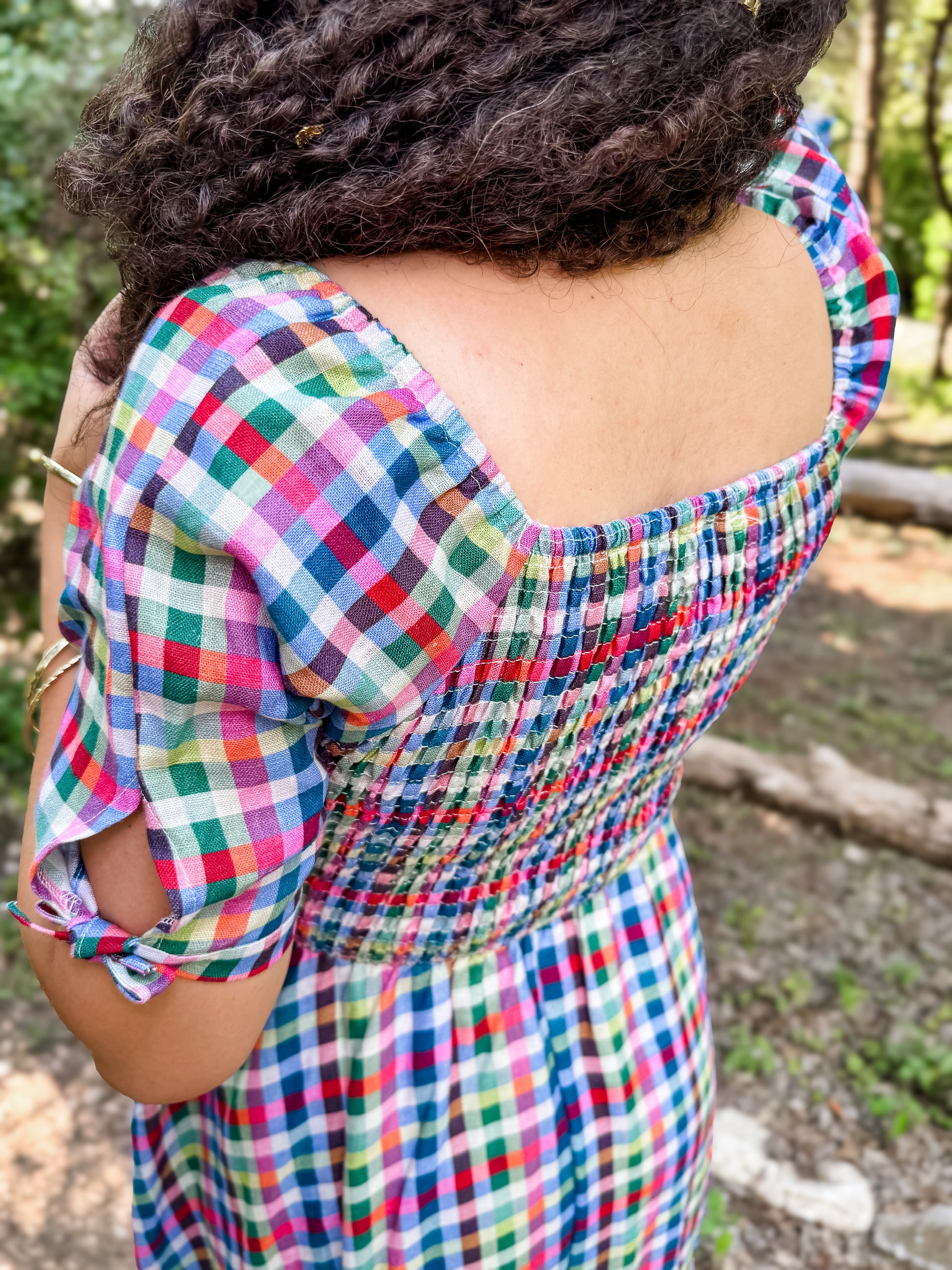 Woman wearing a colorful checkered modest nursing dress with a blurred natural background