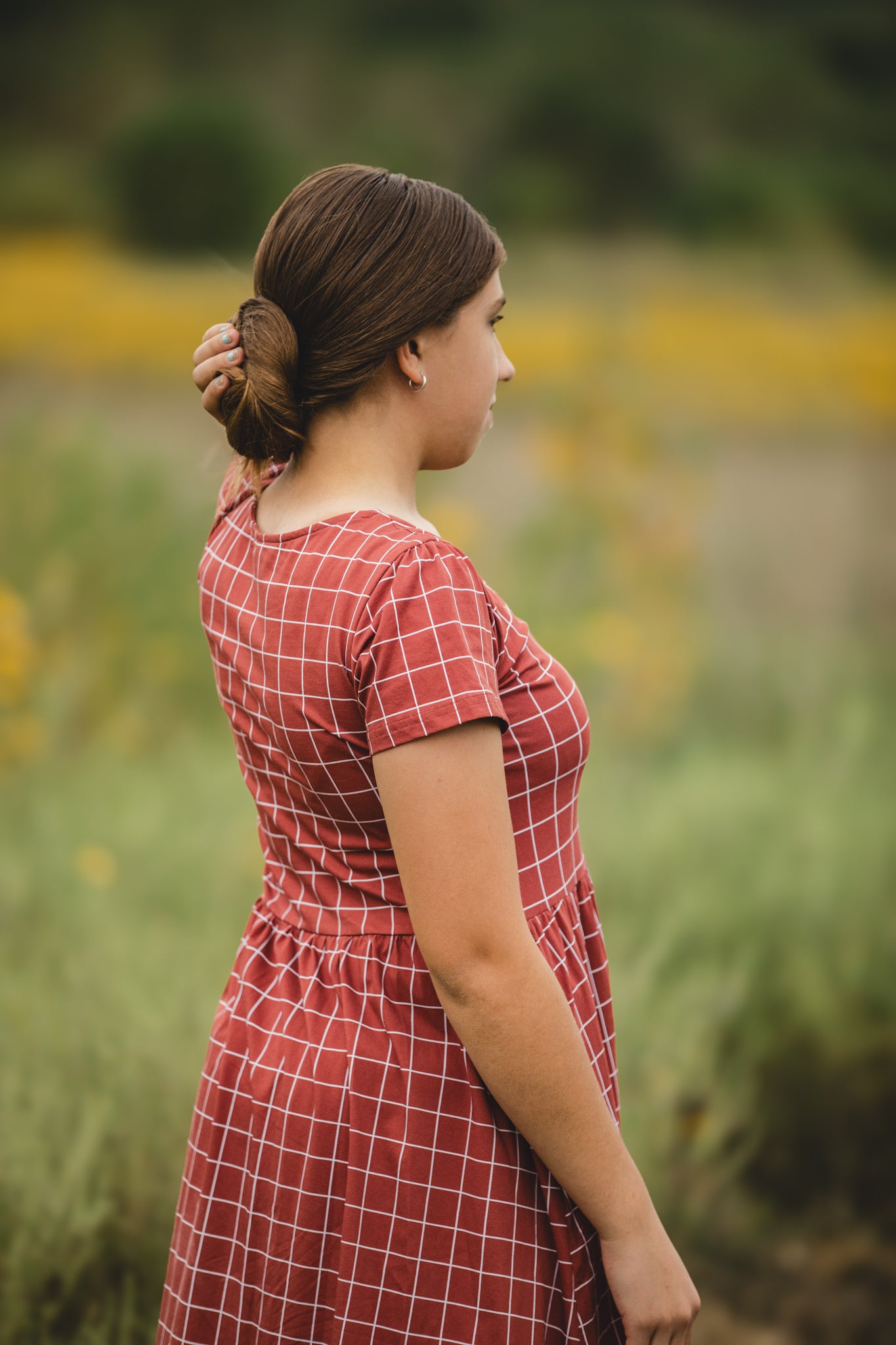 Woman in modest checkered dress, nursing-friendly design.