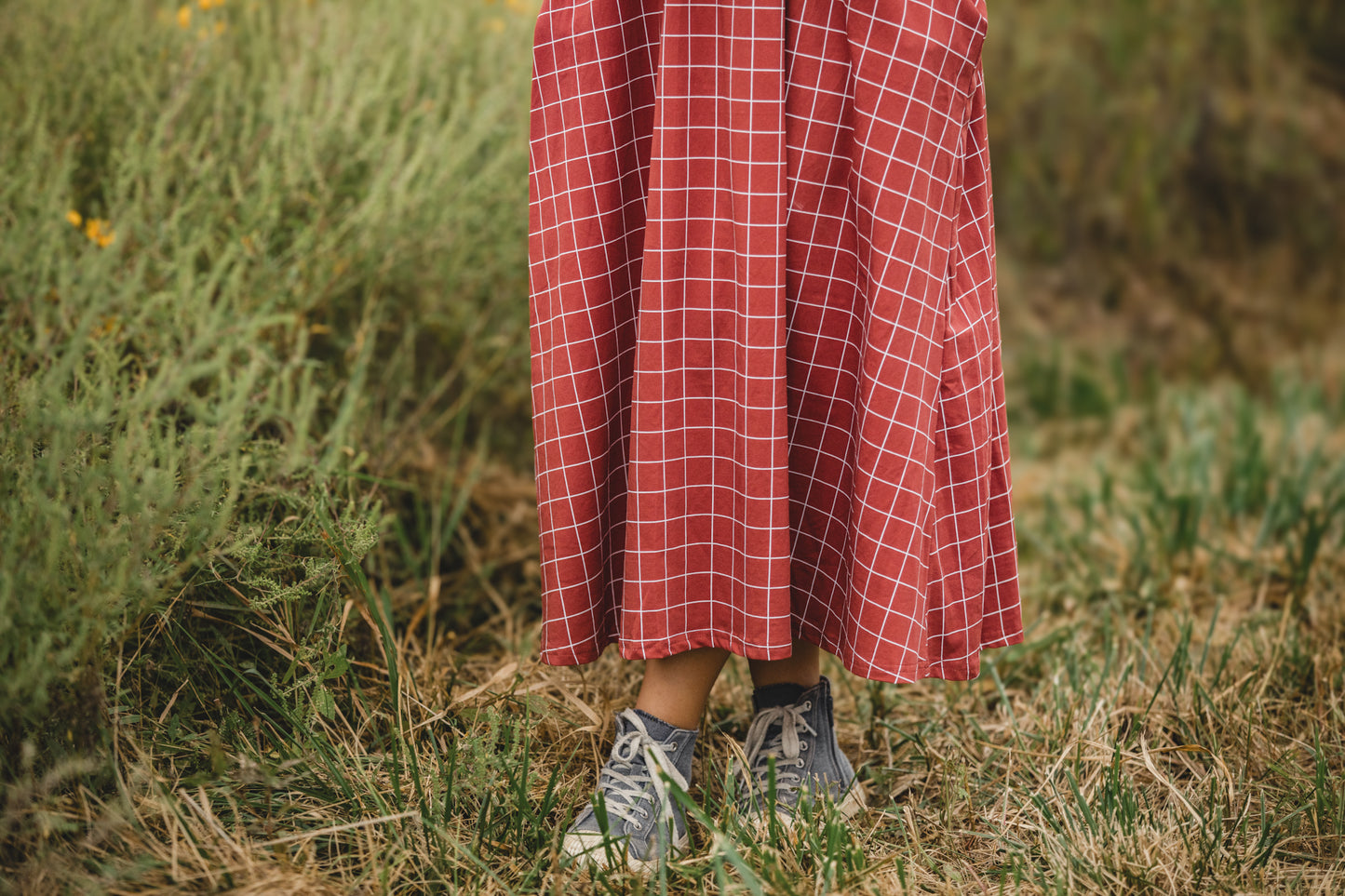 Woman in modest plaid dress, nursing-friendly design.