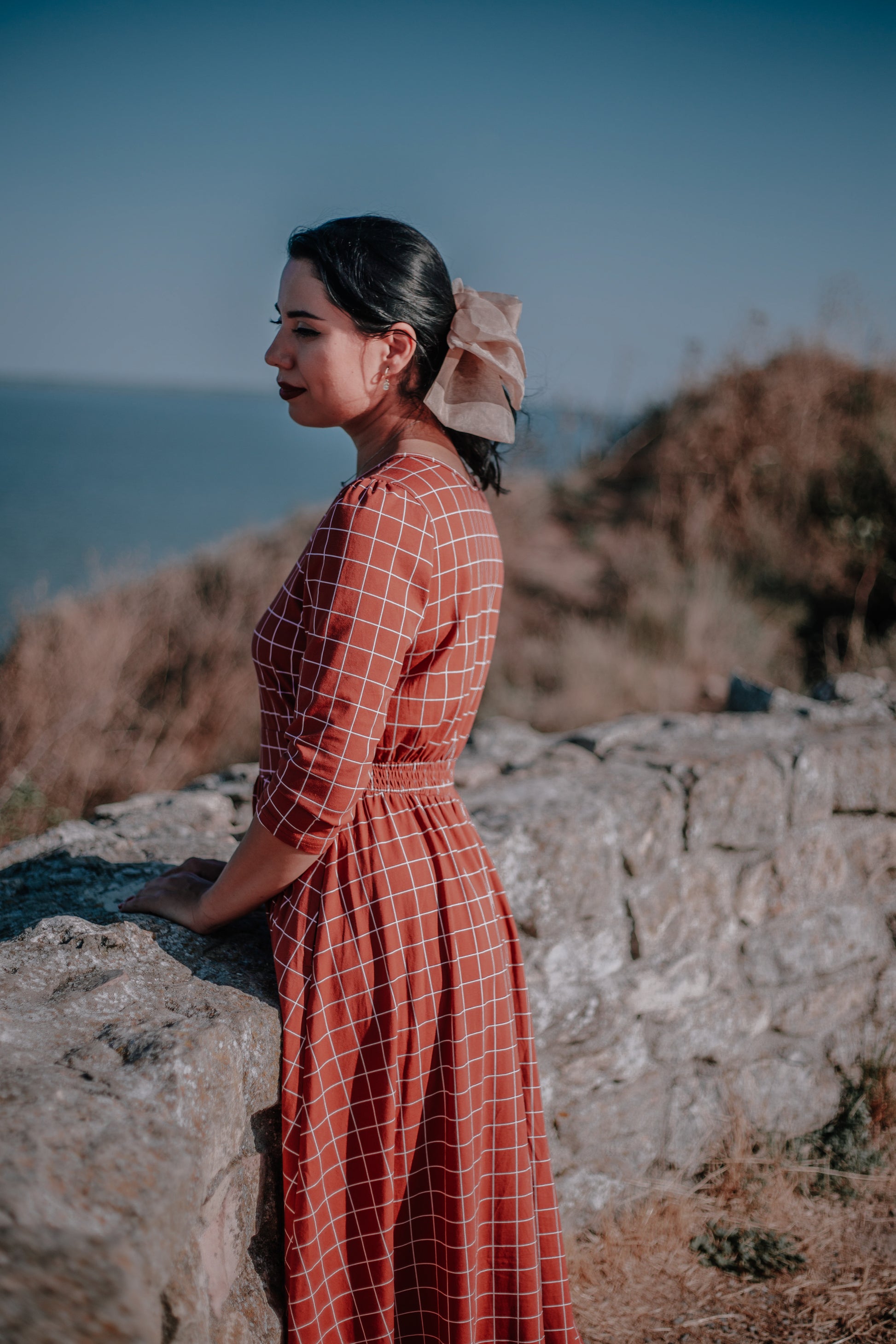 Woman in modest nursing copper windowpane maxi dress