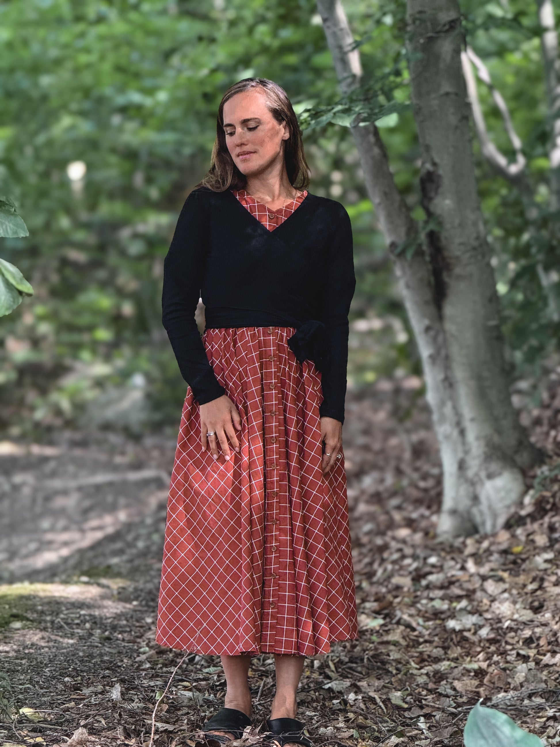Woman in modest nursing red plaid skirt forest