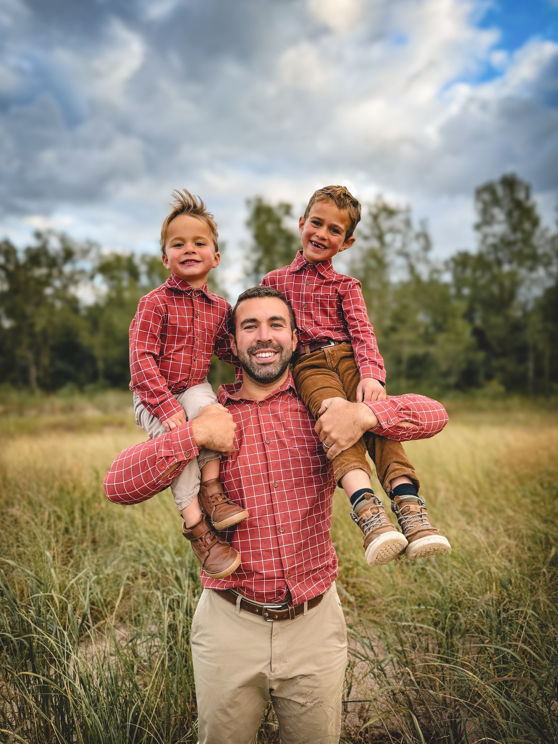 Father with two children on shoulders outdoors