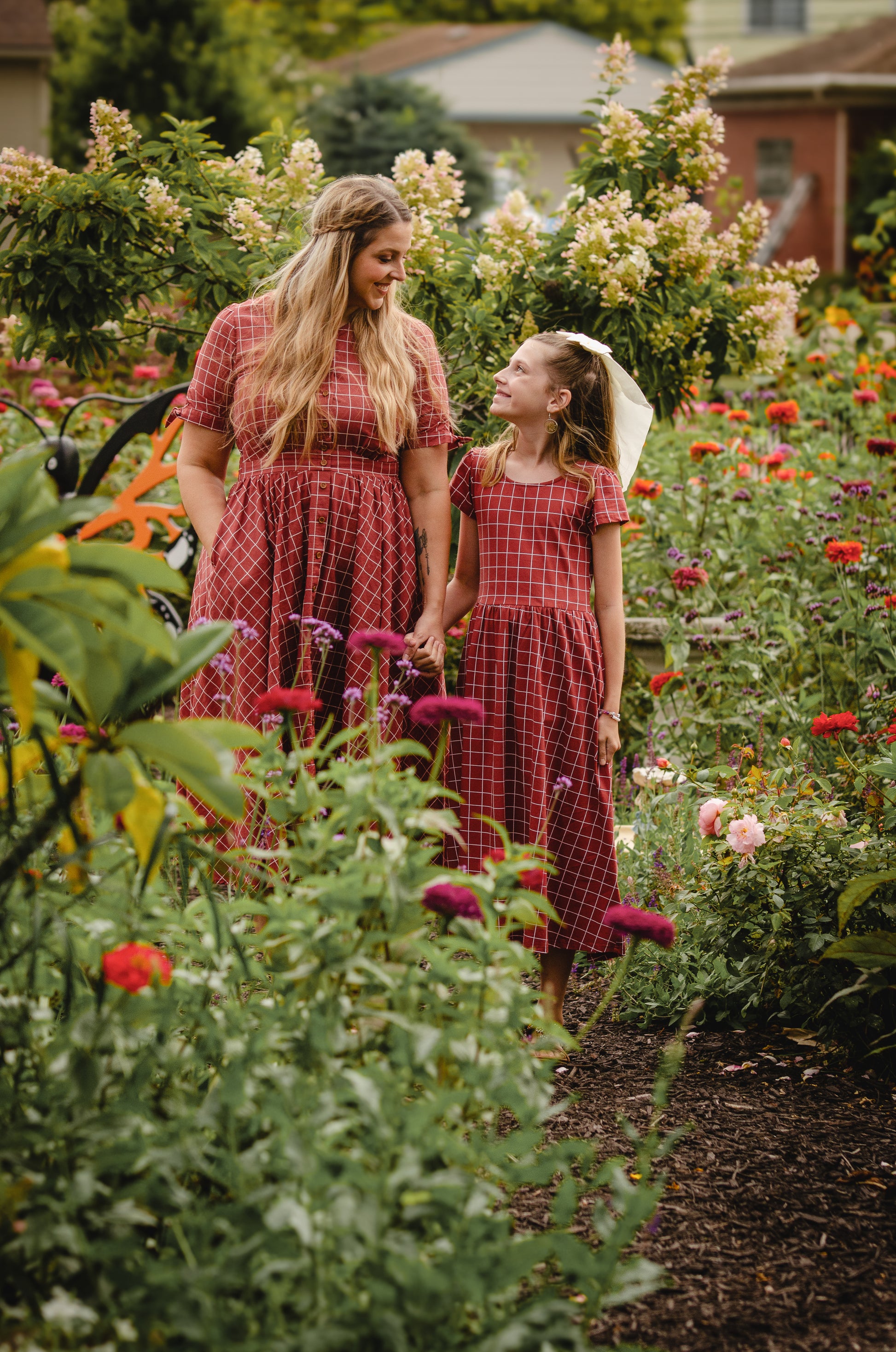 Mother and child in modest nursing red dresses garden flowers