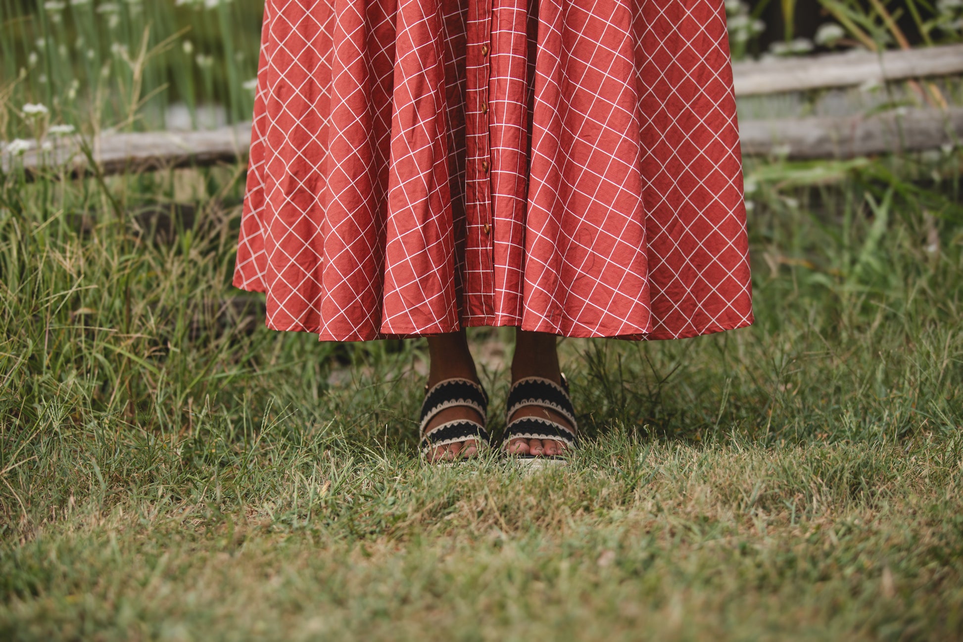 Woman in modest nursing red checkered dress grass