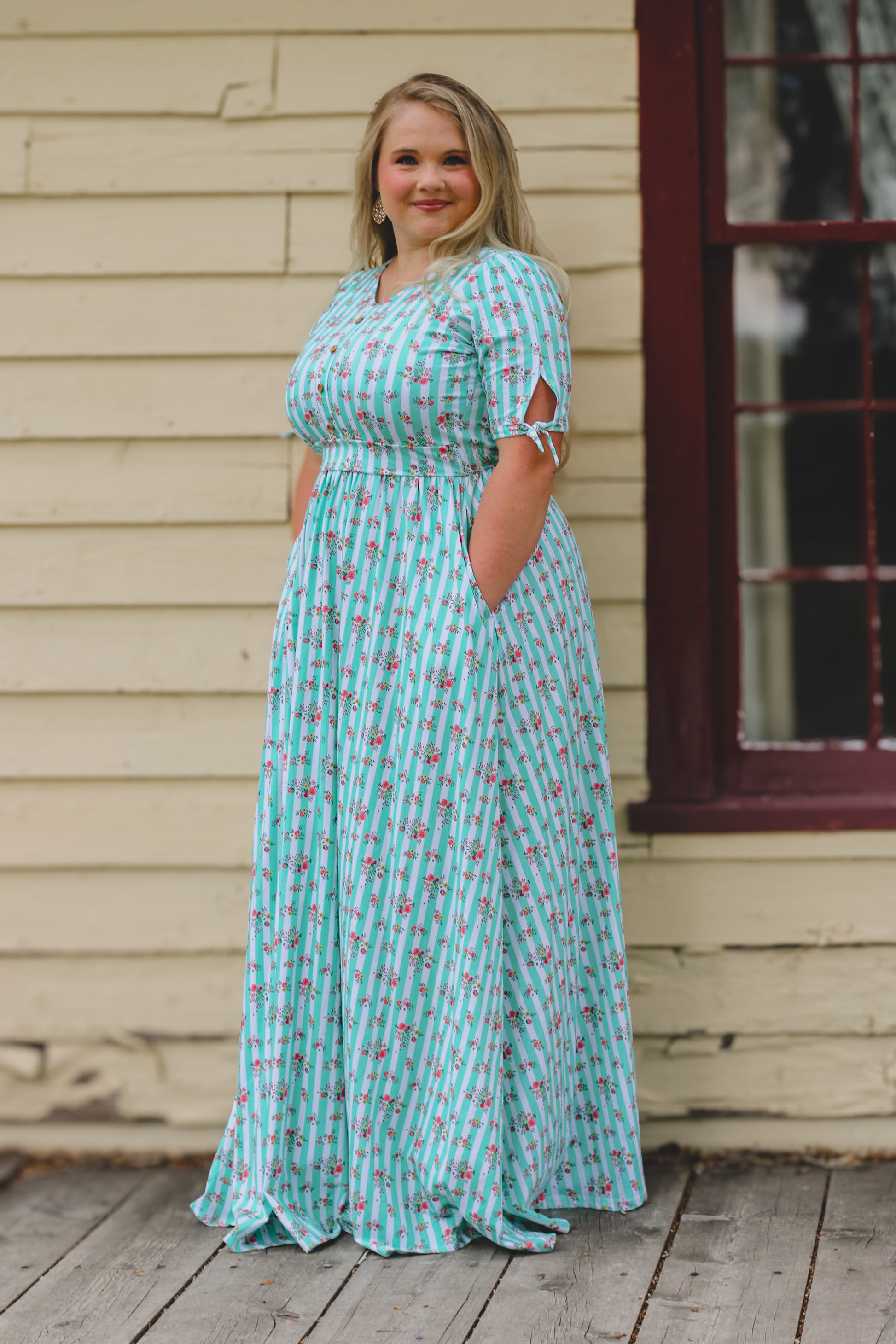 Woman wearing a blue floral modest nursing dress standing on a wooden deck.