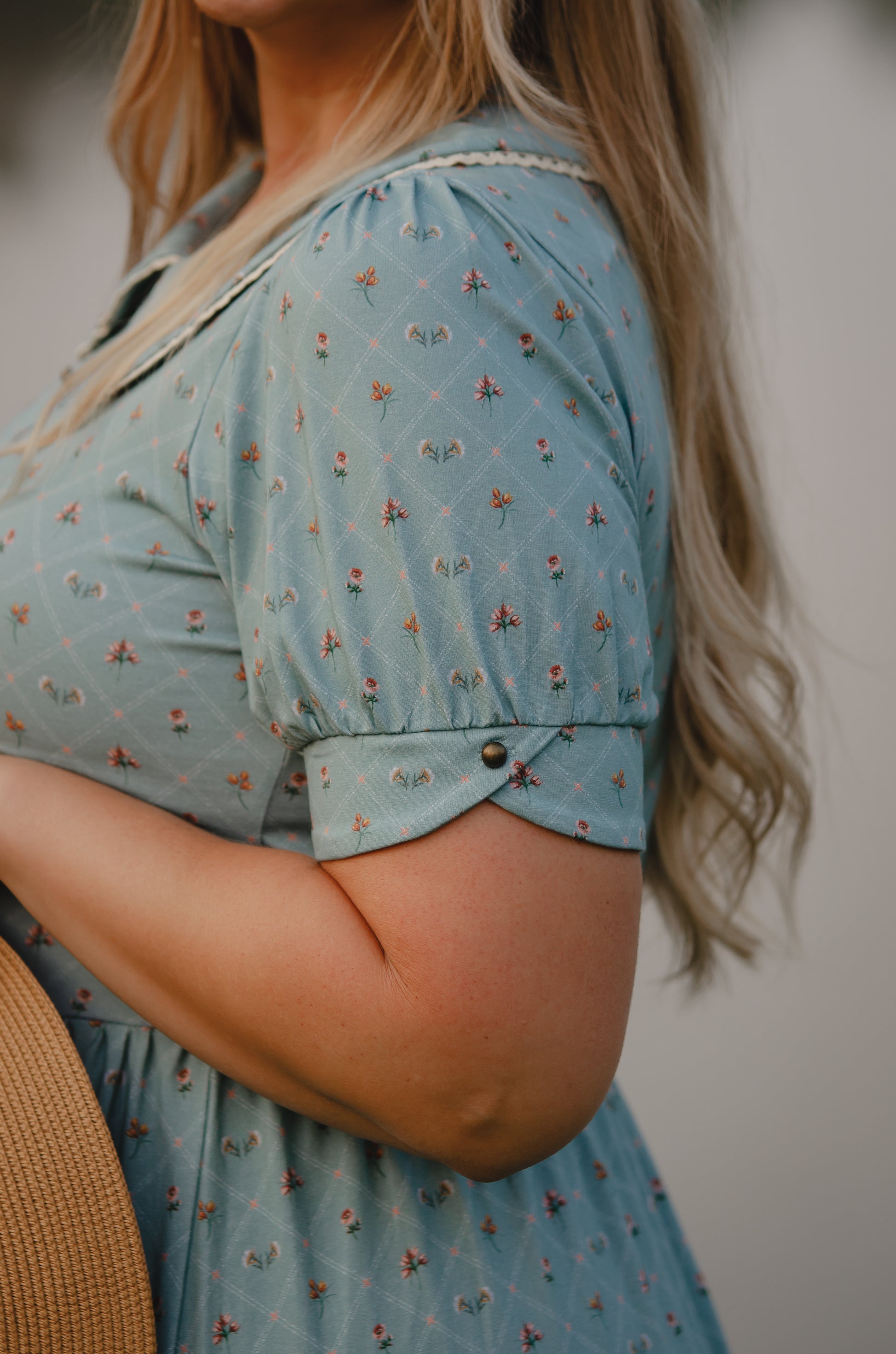 Person wearing a light blue modest nursing dress with a floral pattern, standing outdoors.