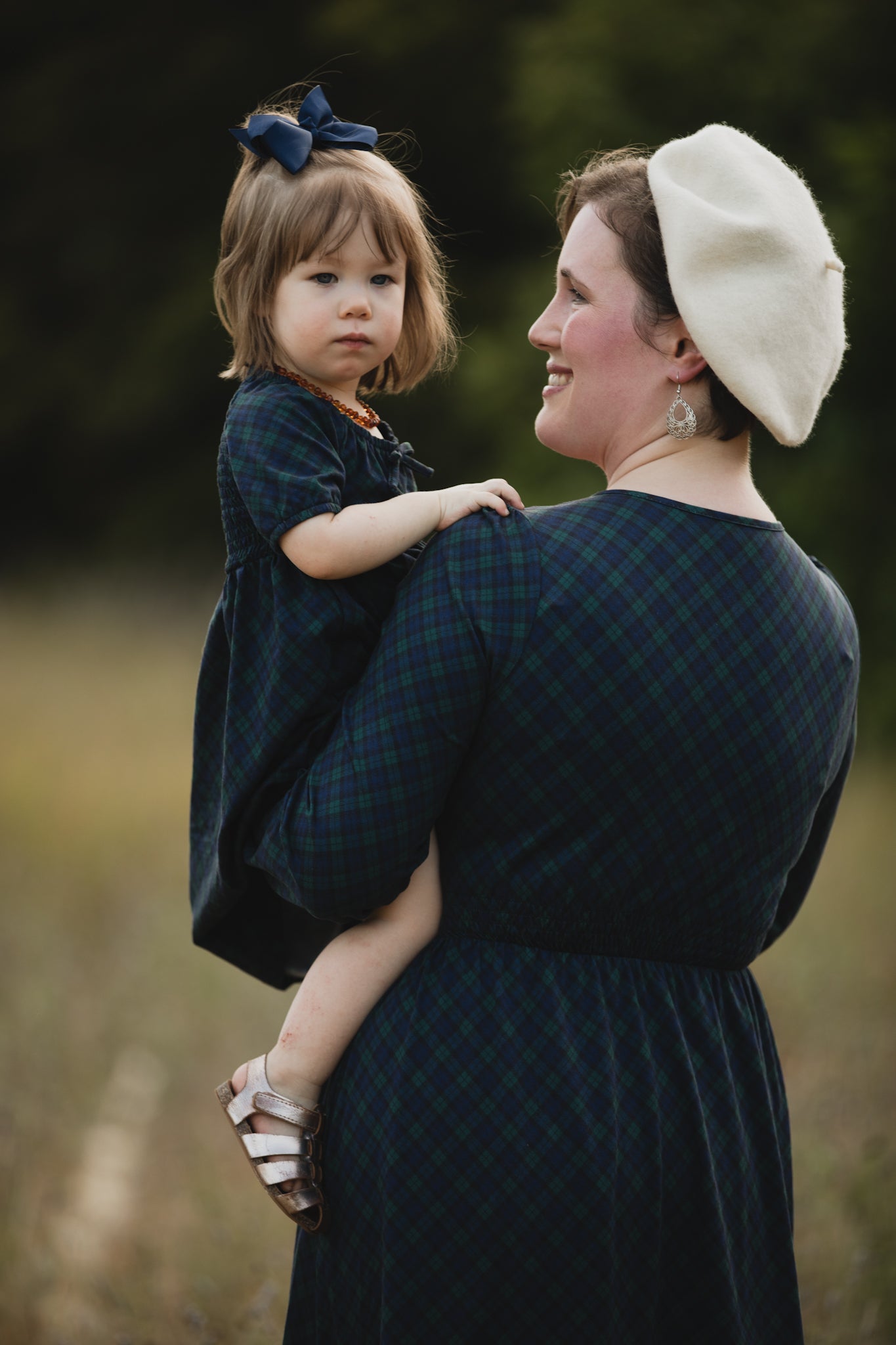 Woman in modest nursing dress with child in field
