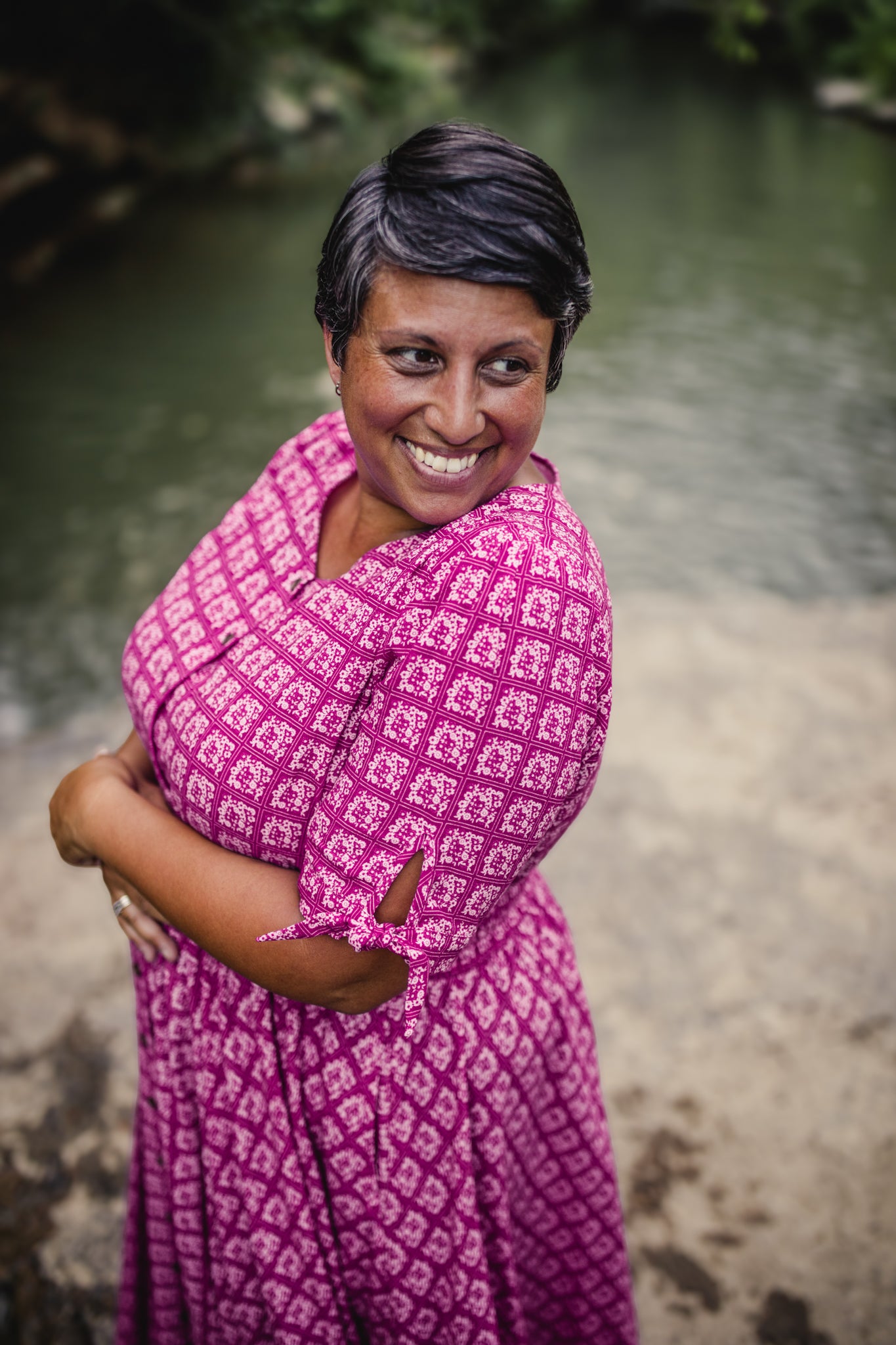Woman wearing a pink patterned modest nursing dress standing outdoors with a natural background