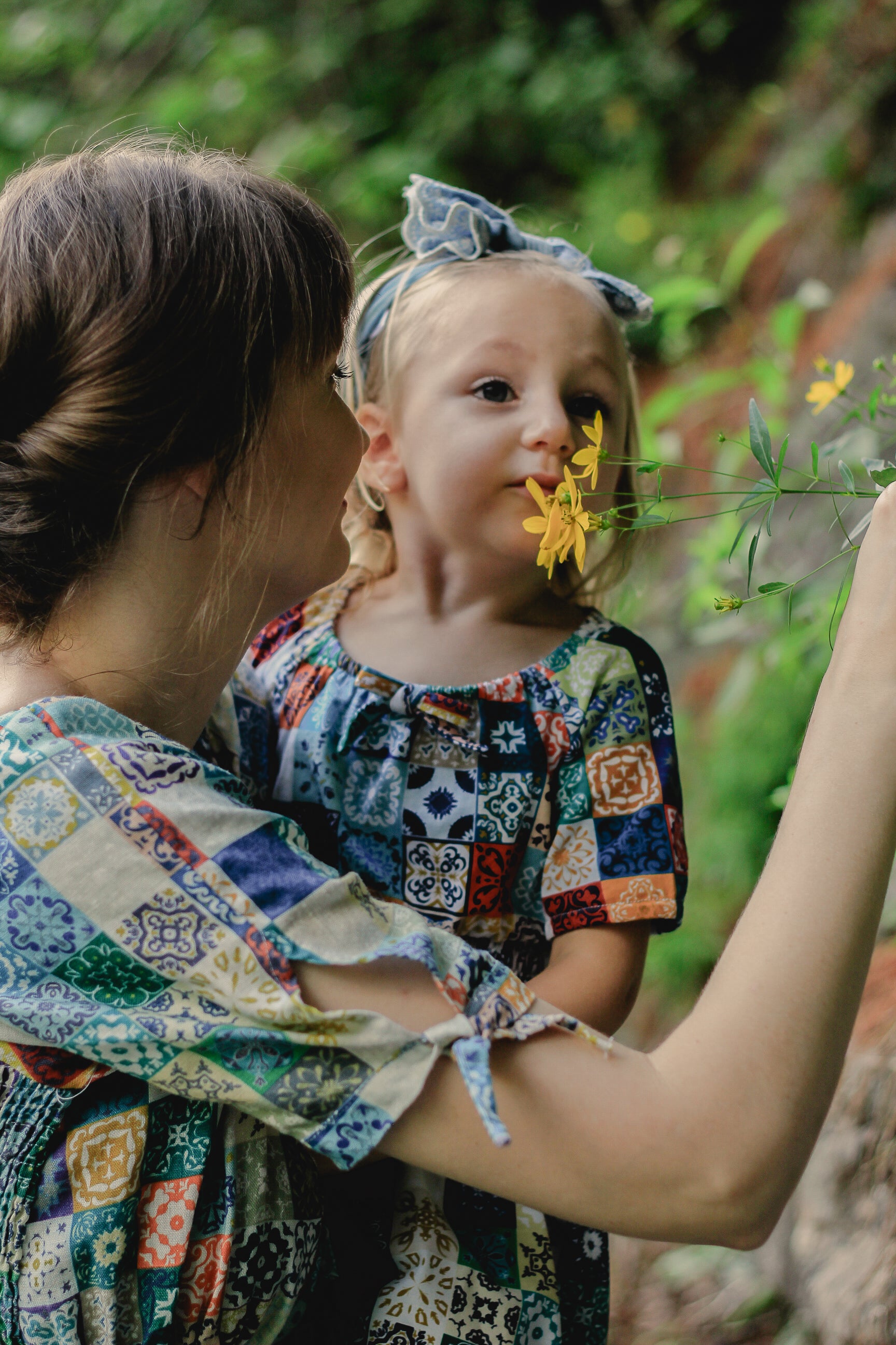 Woman holding a child with a flower in a modest nursing dress