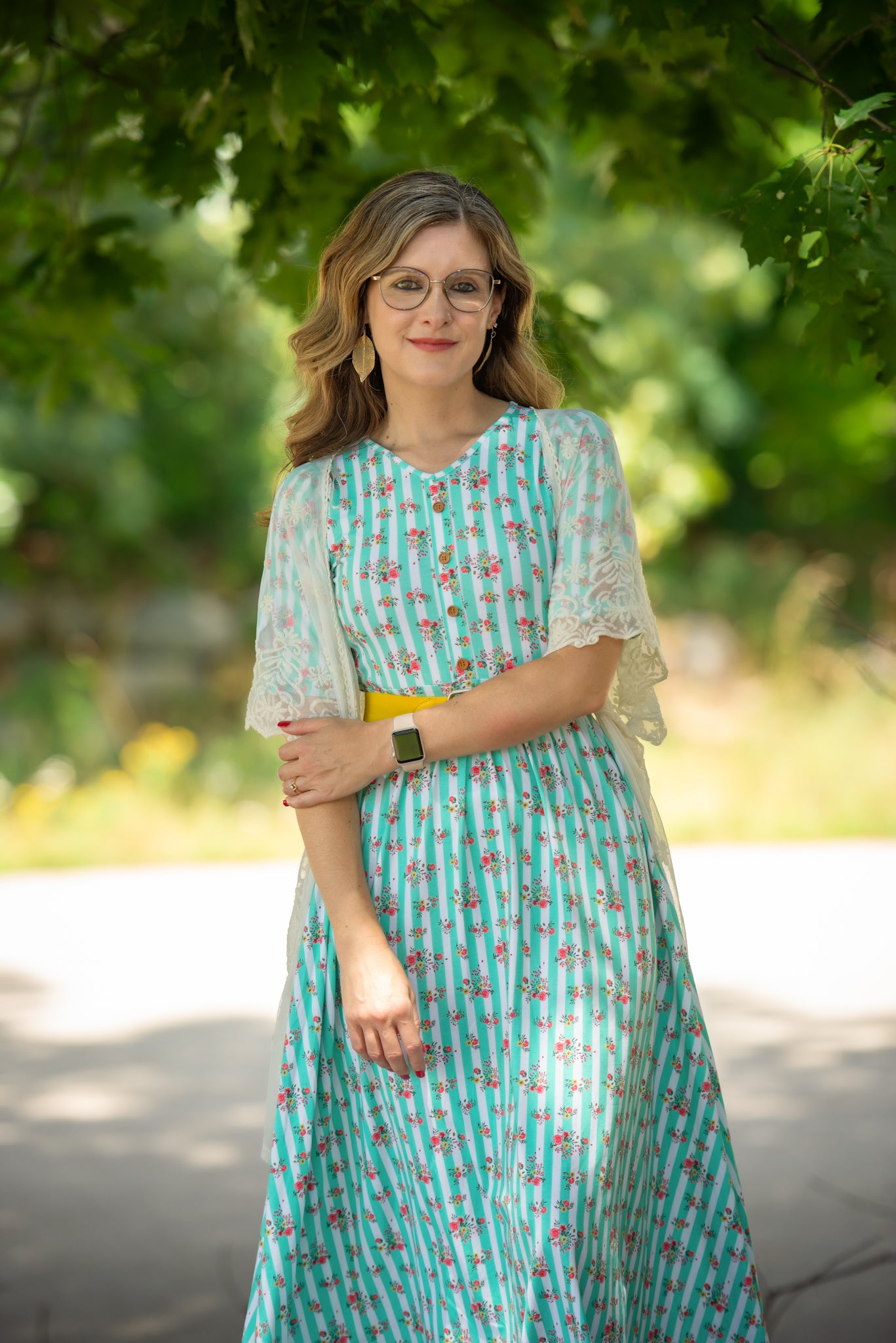 Woman in a floral modest nursing dress standing outdoors with greenery in the background