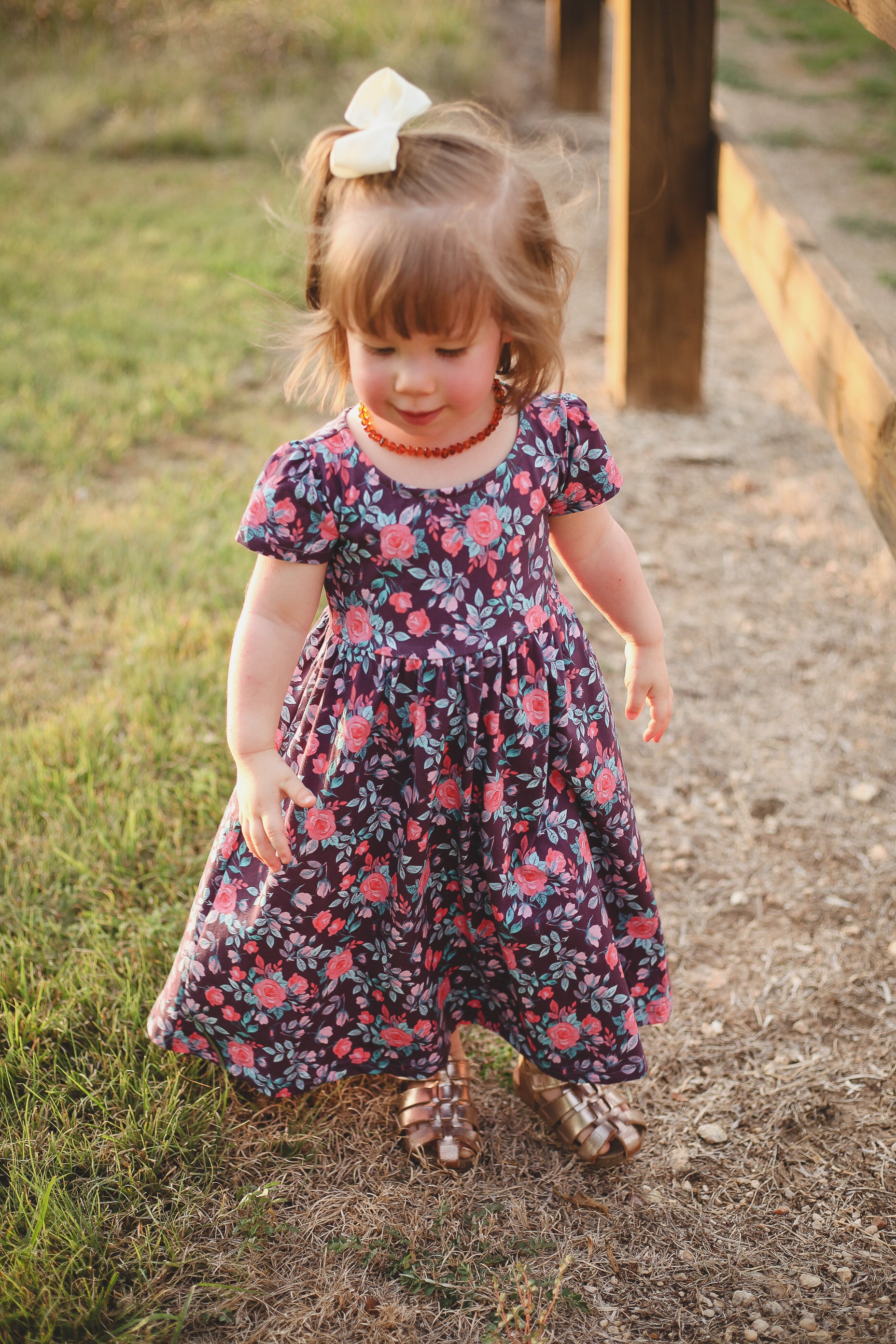 Child in floral dress standing outdoors