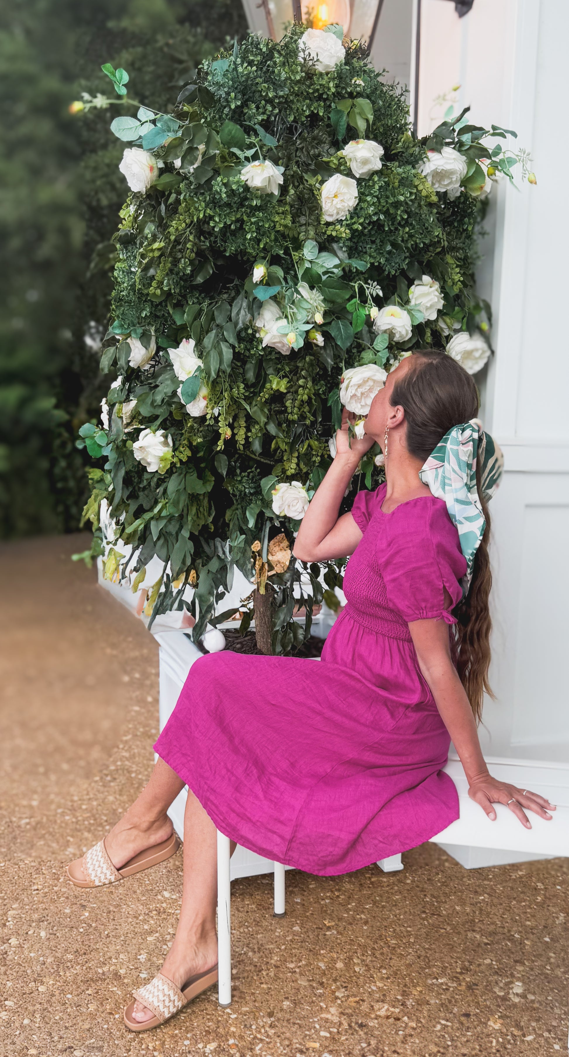Woman in a pink modest nursing dress sitting in front of a floral arrangement.