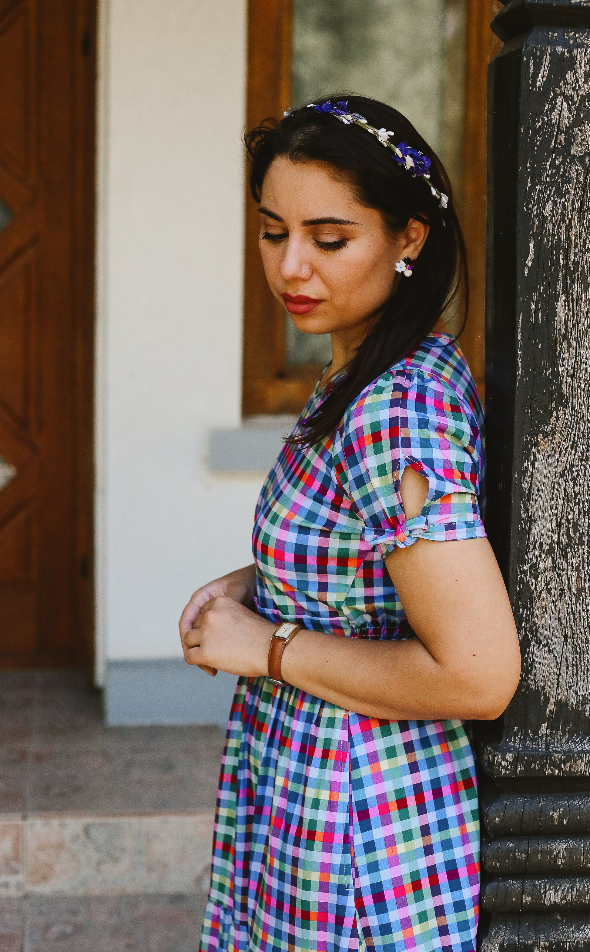 Woman wearing a colorful checkered modest nursing dress standing against a wall.