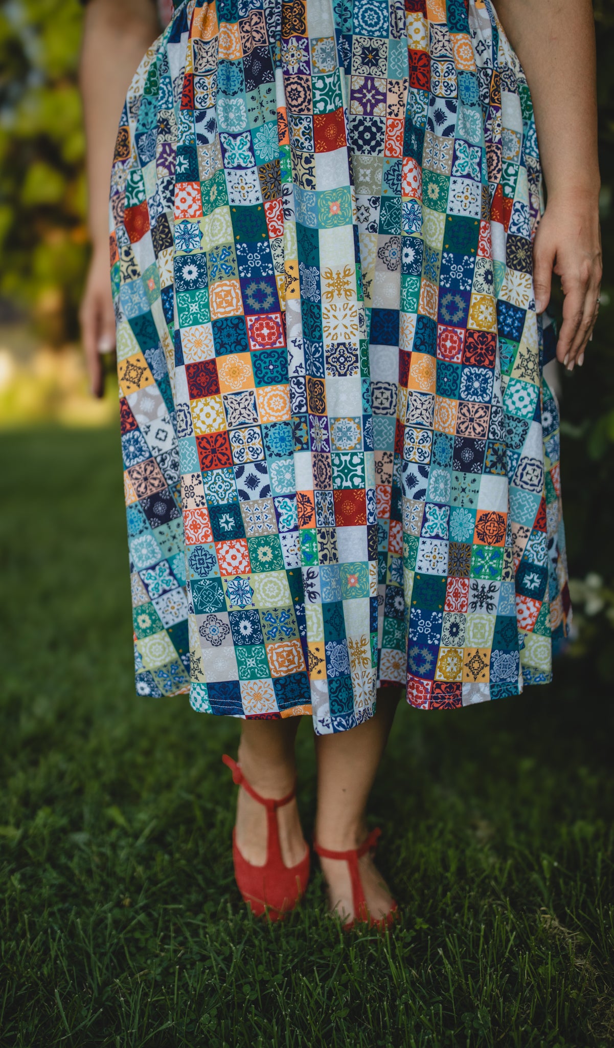 Person wearing a colorful patchwork modest nursing dress standing on grass