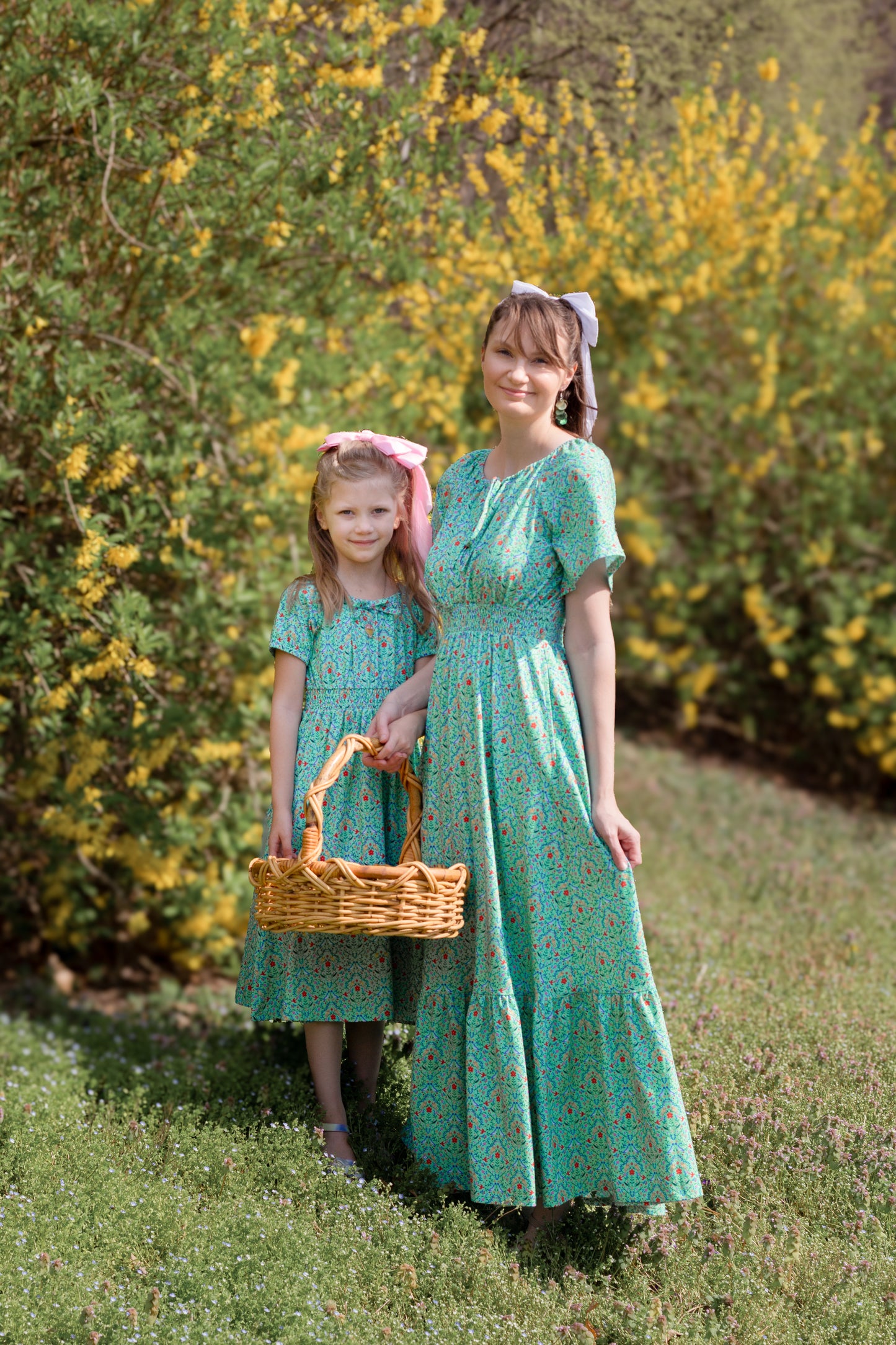 Young girl wearing a modest green dress with her mother in a modest green nursing dress